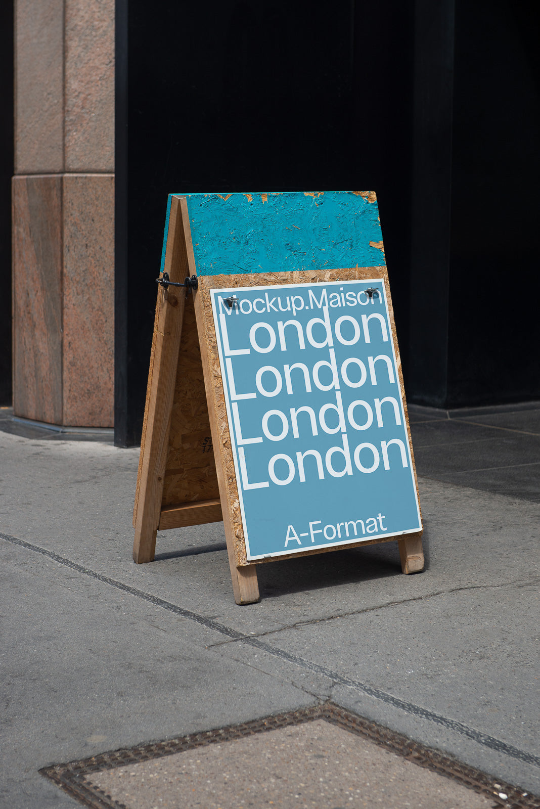 PSD mockup of an A-frame sign on a sidewalk featuring the text "London" repeated four times on a blue background with "Mockup.Maison" and "A-Format."