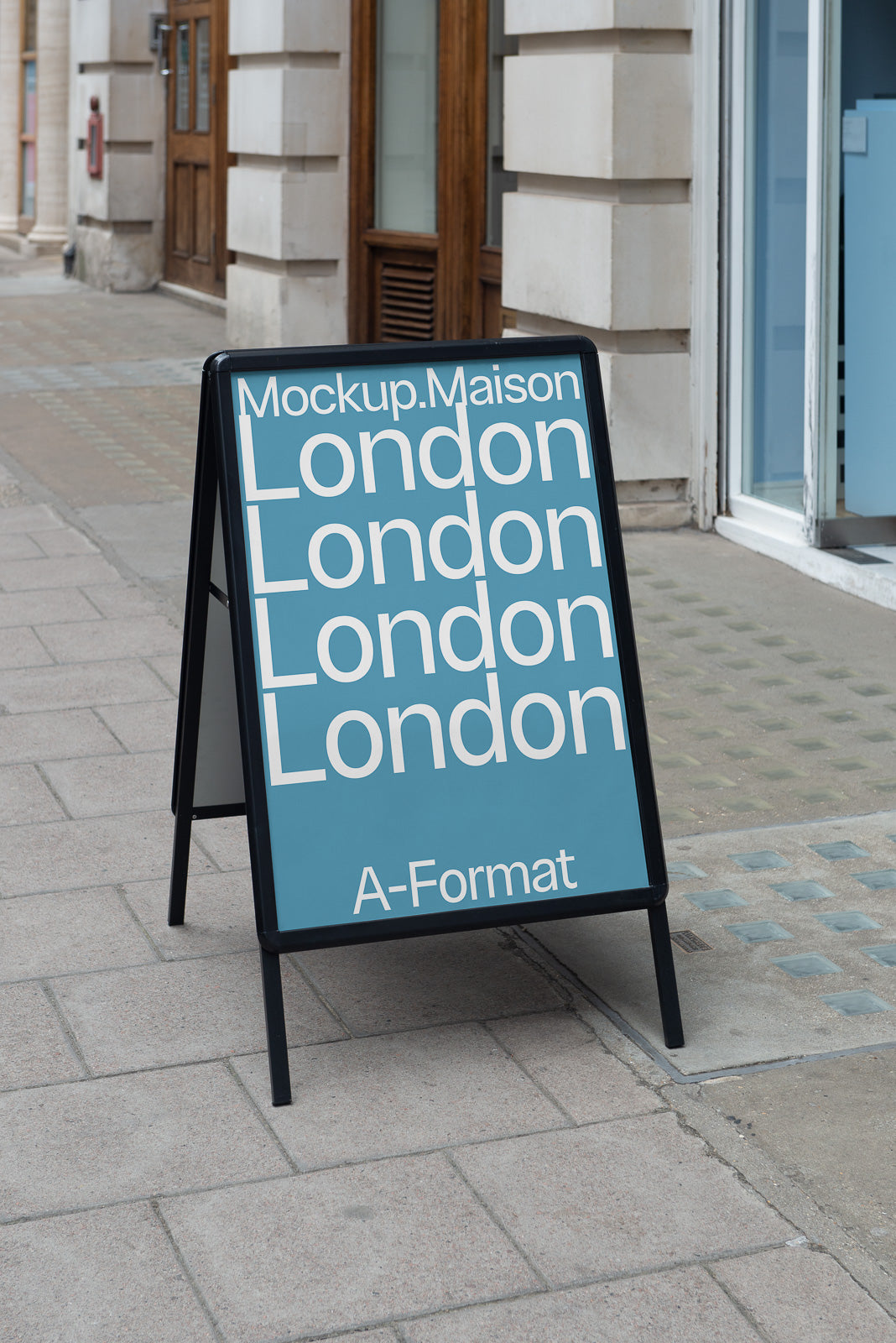 PSD mockup of an A-frame sidewalk sign displaying the text "Mockup.Maison London London London London A-Format" against a blue background on a city street.