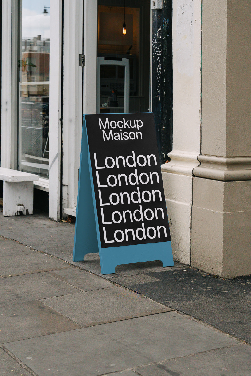 PSD mockup of a sidewalk sandwich board with the text "Mockup Maison" and "London" repeated, placed in front of a store entrance.