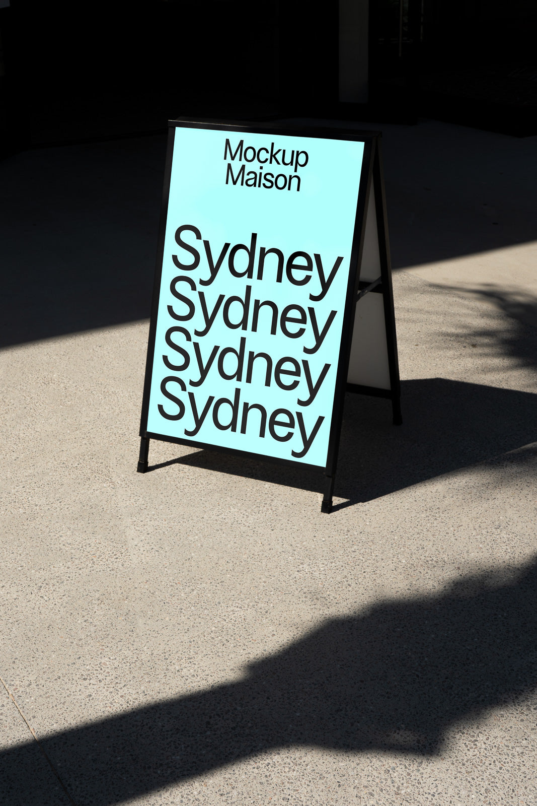 PSD mockup of a standing signboard on a sidewalk, displaying text "Sydney" in bold letters against a light blue background.