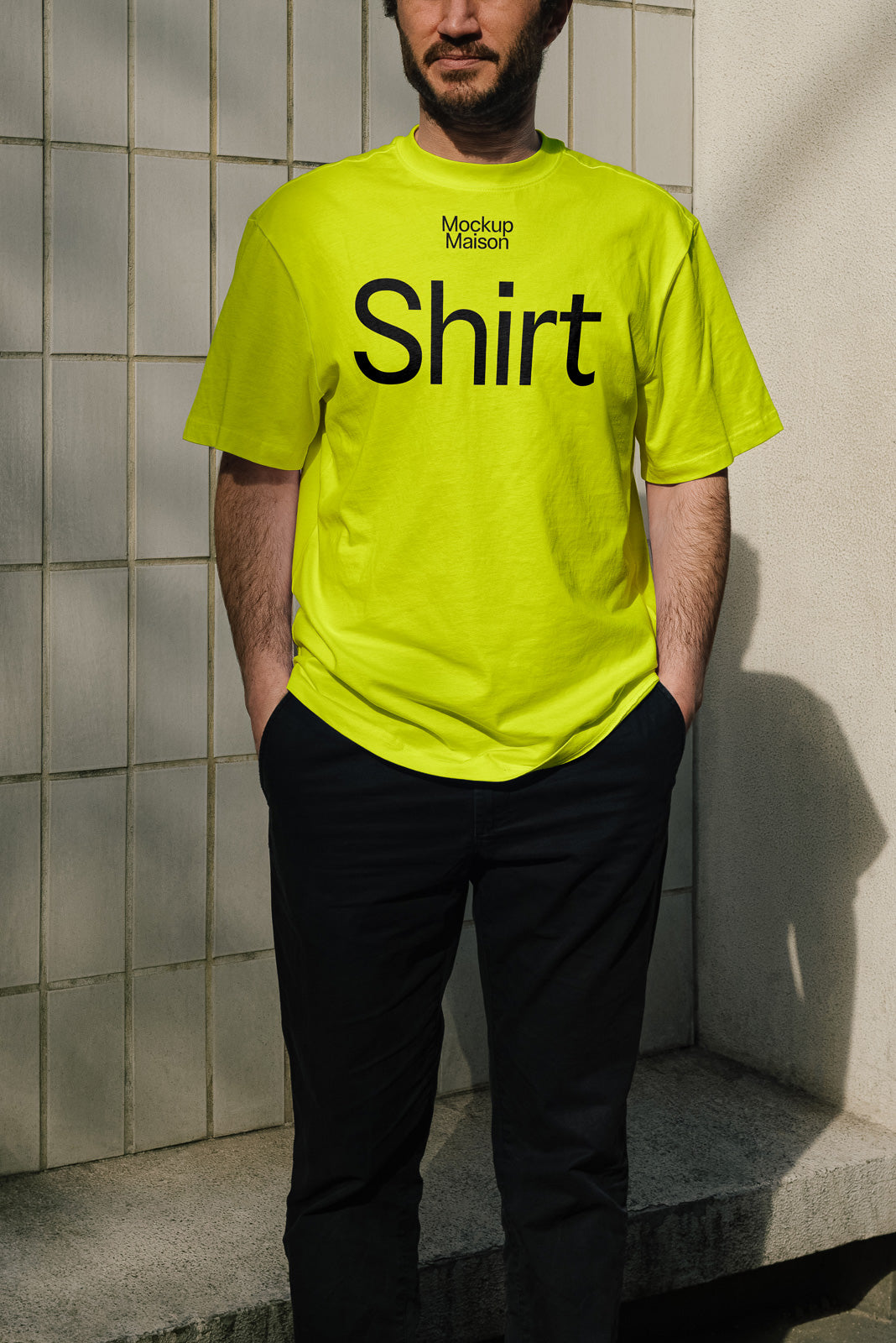 PSD mockup of a person wearing a neon yellow T-shirt with "Shirt" printed in bold black text, standing in front of a tiled wall.