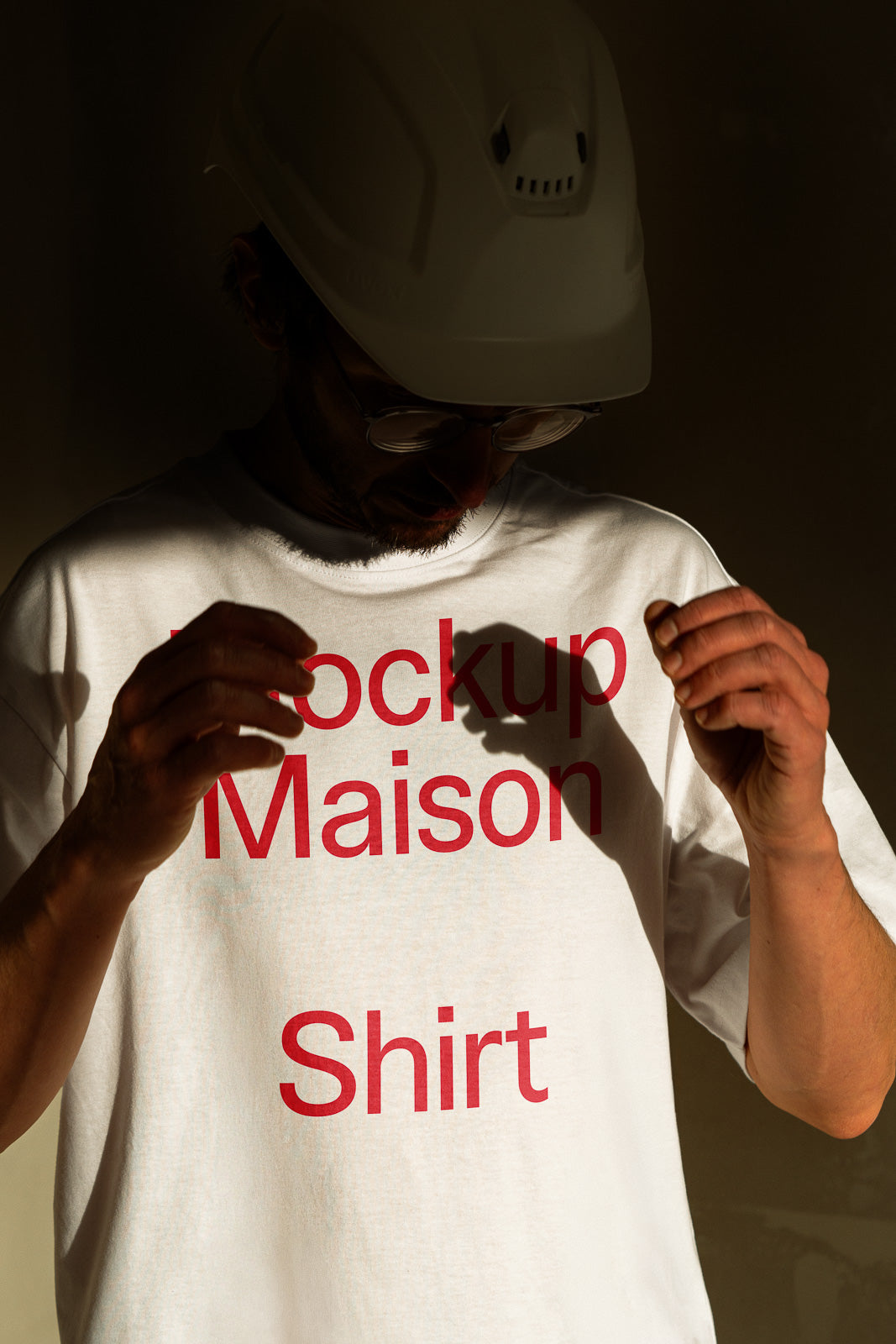 PSD mockup of a person wearing a white T-shirt with red text, captured in dramatic lighting, emphasizing shadows and highlights.