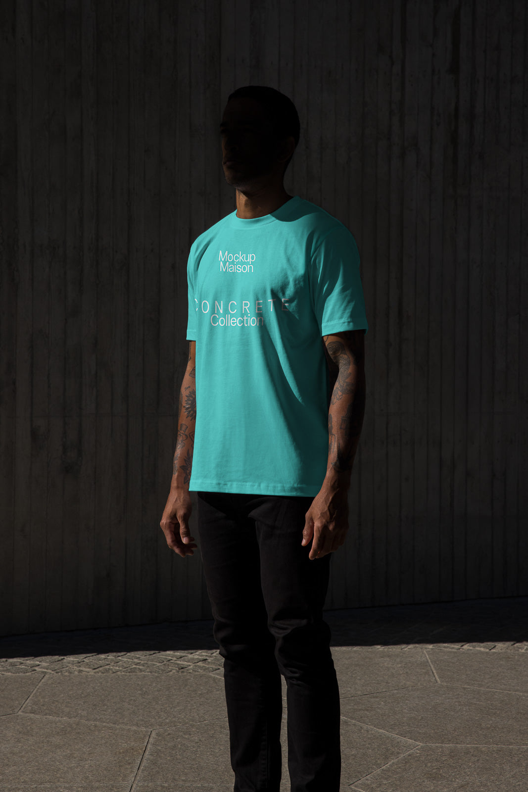 PSD mockup of a person in a teal t-shirt with "Mockup Maison Concrete Collection" text, set against a textured, dark concrete background.