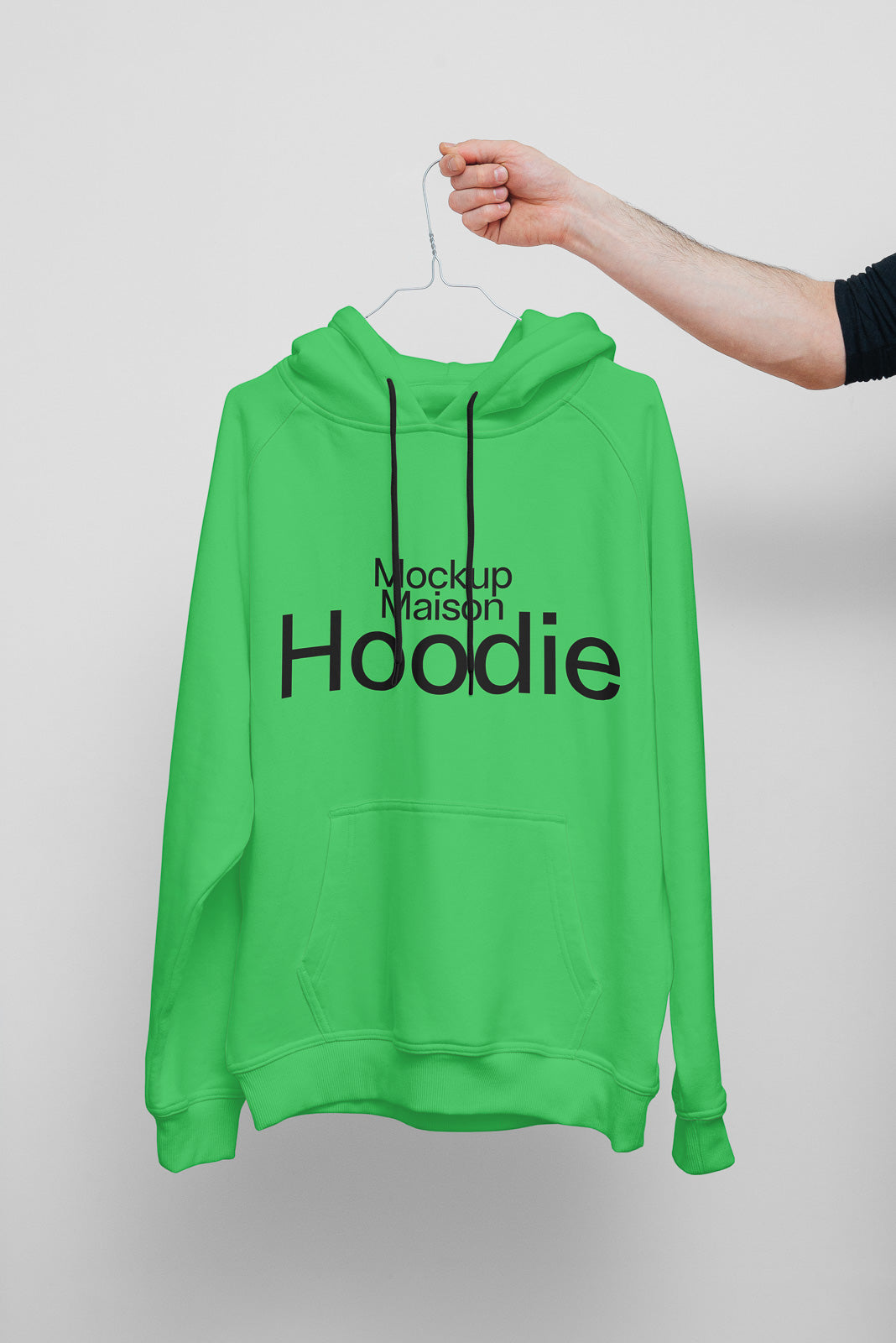 PSD mockup of a green hoodie hanging on a wire hanger held by a hand, with "Mockup Maison Hoodie" text on the front.