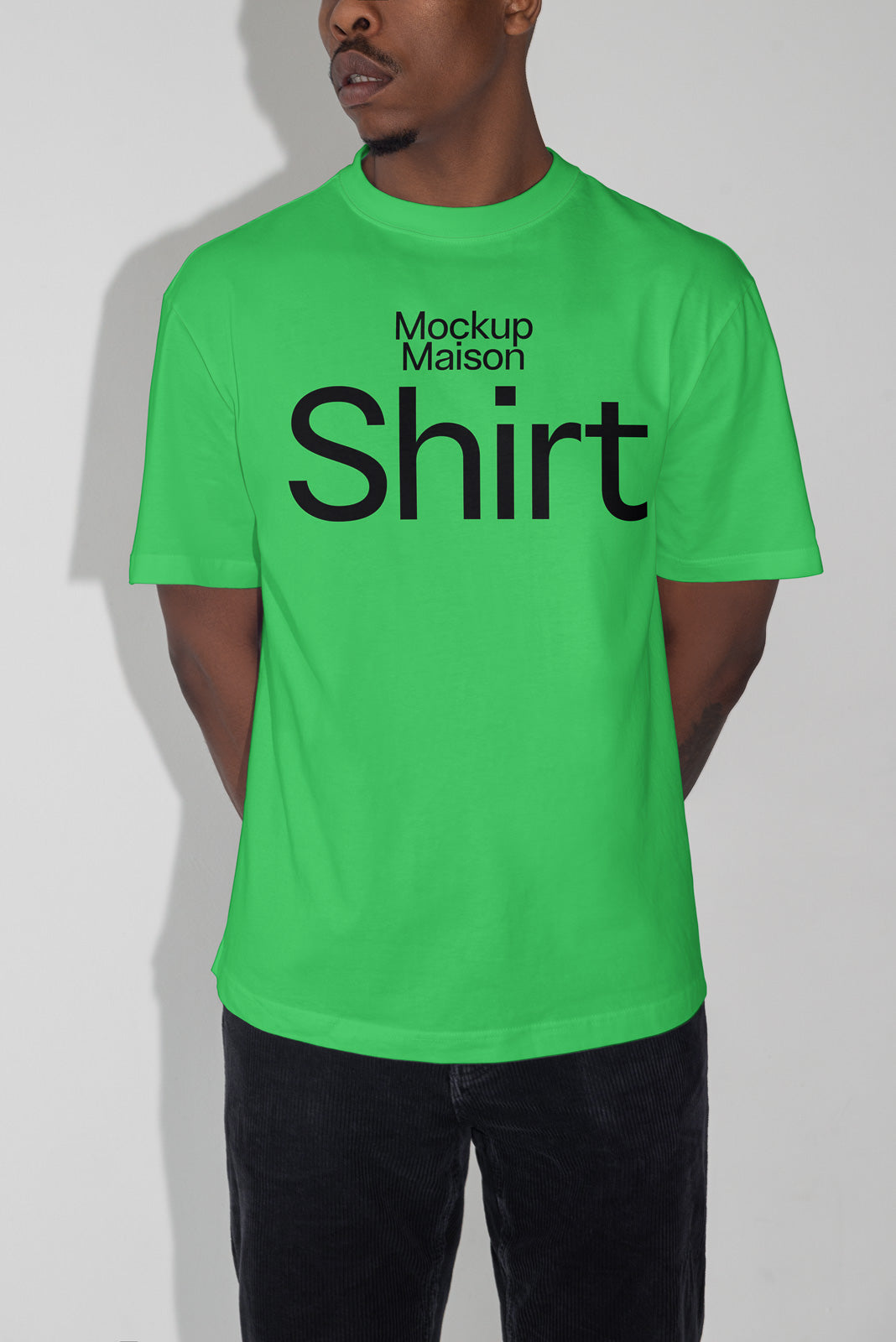 PSD mockup of a bright green T-shirt with "Mockup Maison Shirt" printed in bold black letters, modeled by a person against a plain background.