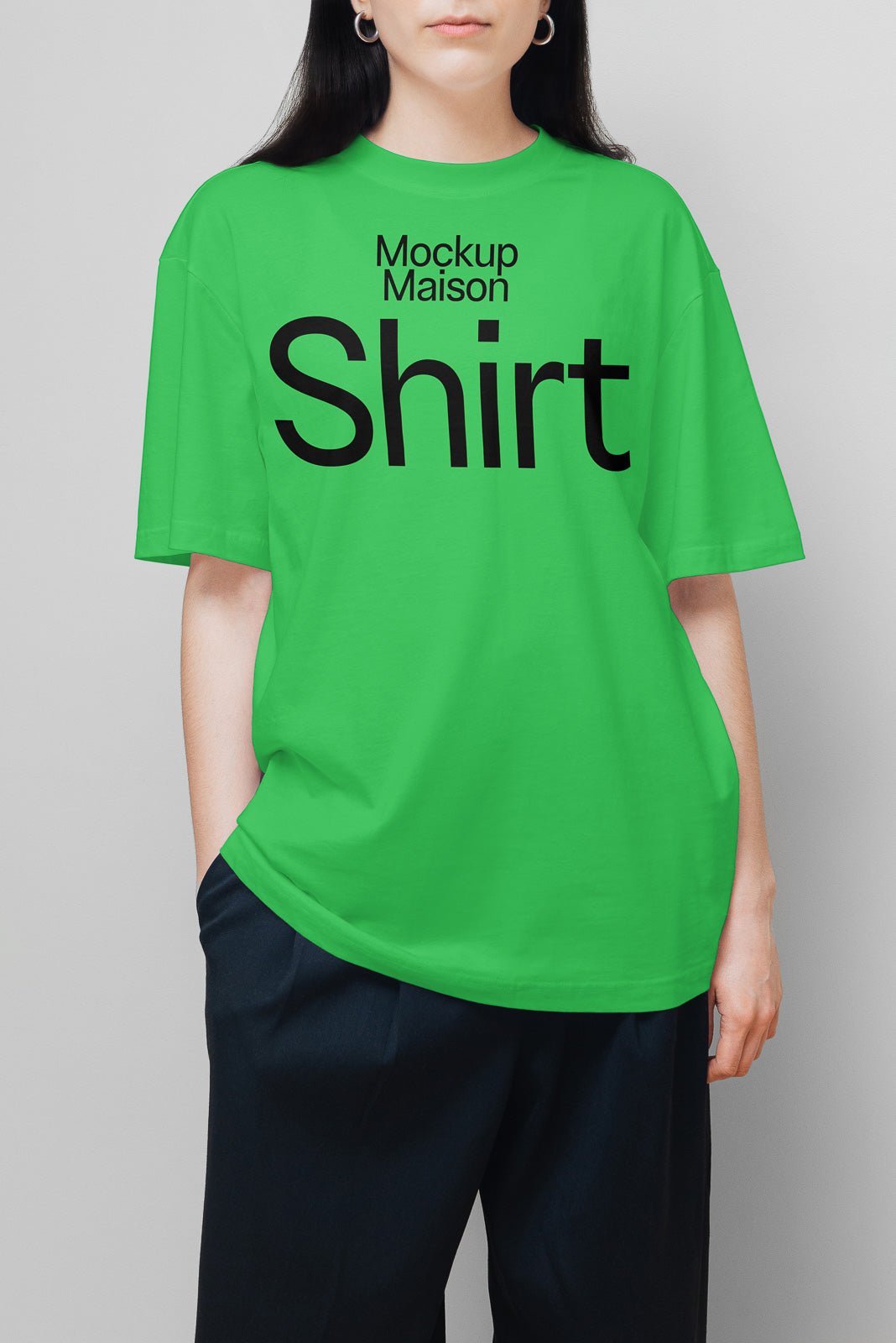 PSD mockup of a person wearing a bright green t-shirt with black text "Mockup Maison Shirt," paired with dark pants, standing against a plain background.