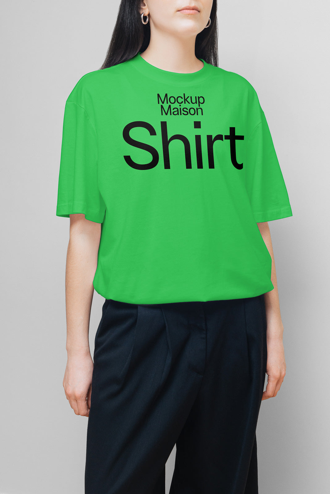 PSD mockup of a green T-shirt with "Mockup Maison Shirt" text in black, worn by a person paired with dark pants.