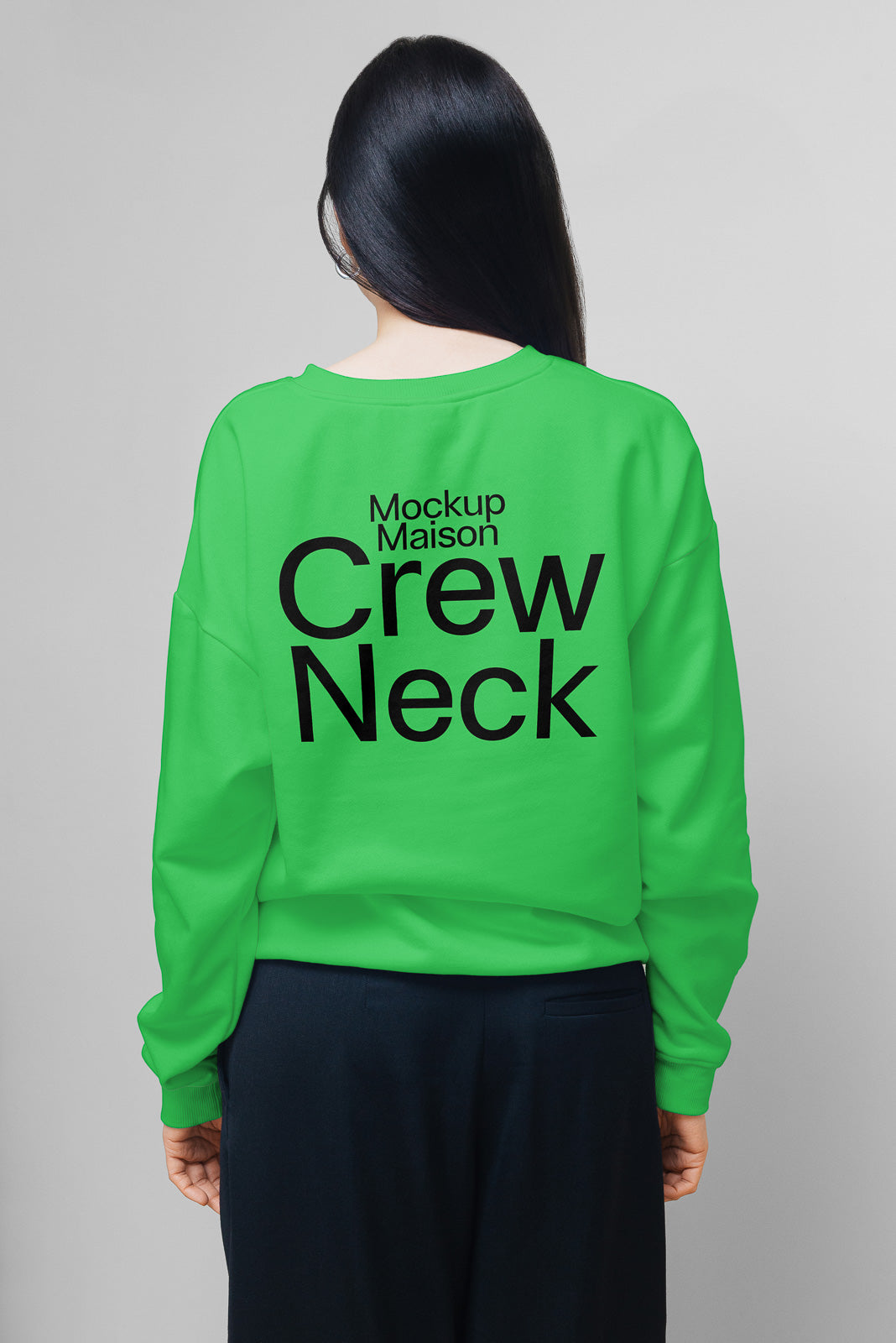 PSD mockup of a person wearing a green crew neck sweatshirt with "Mockup Maison Crew Neck" printed on the back, seen from behind on a plain gray background.