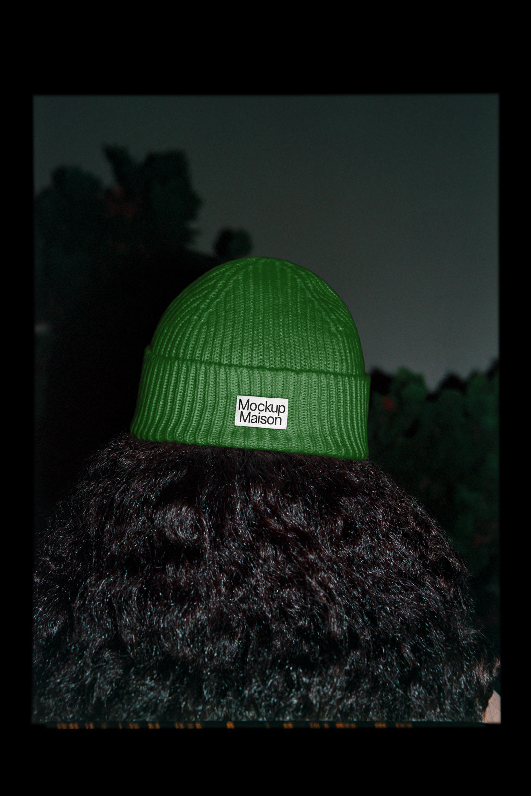 PSD mockup of a person wearing a green beanie labeled "Mockup Maison" against a dark background. The focus is on the textured knit and label detail.