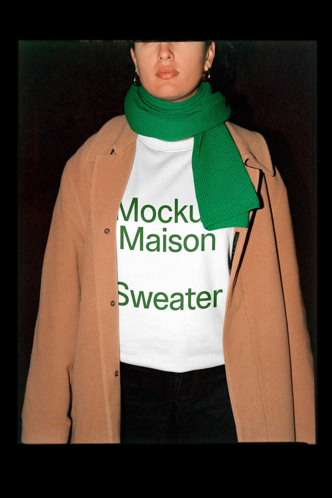 PSD mockup of a person in a brown coat and green scarf, with a white sweater showing the text "Mockup Maison Sweater" in green letters.