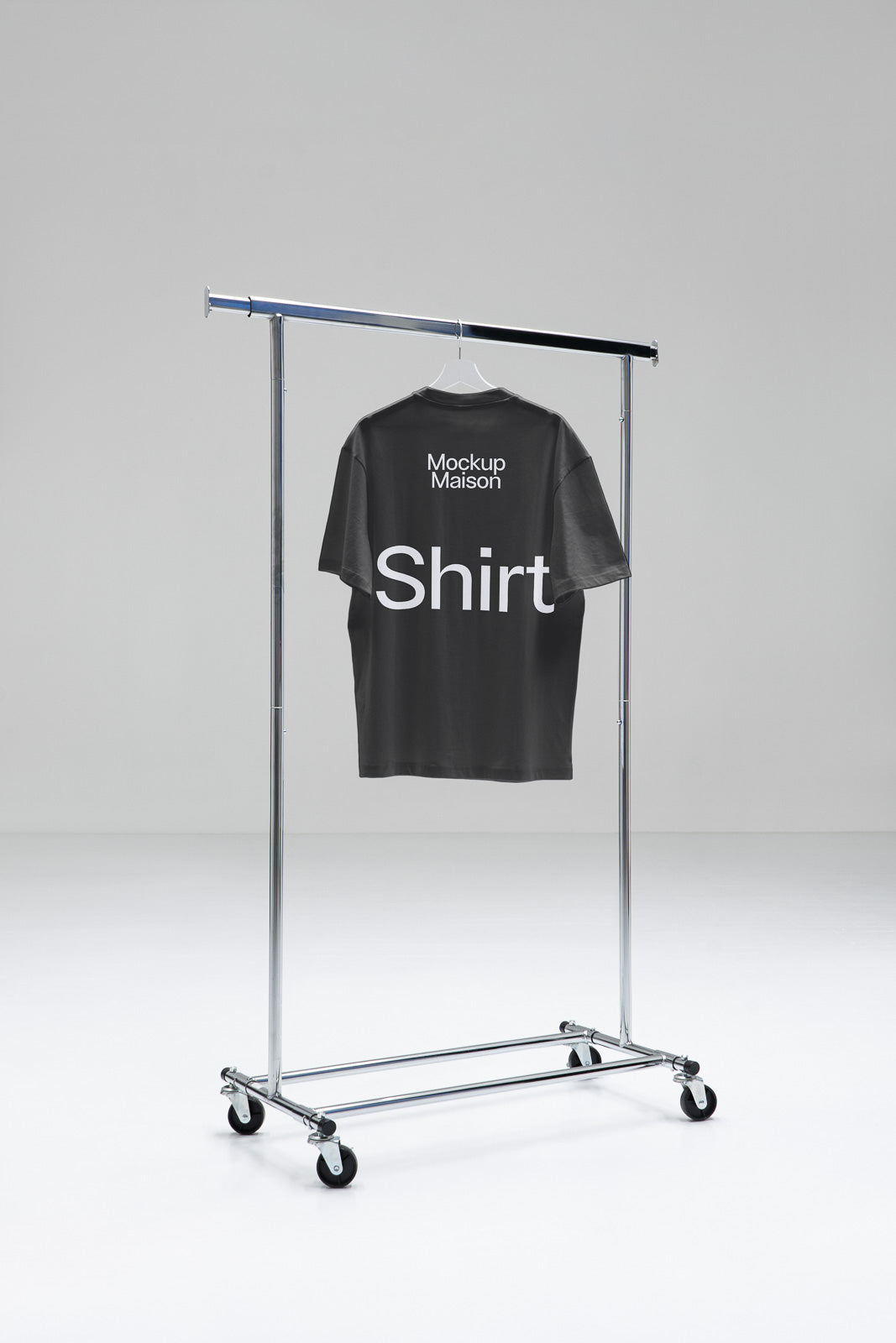 PSD mockup of a black T-shirt hanging on a metal clothing rack, displaying the text "Mockup Maison Shirt" on the back in a minimal studio setting.