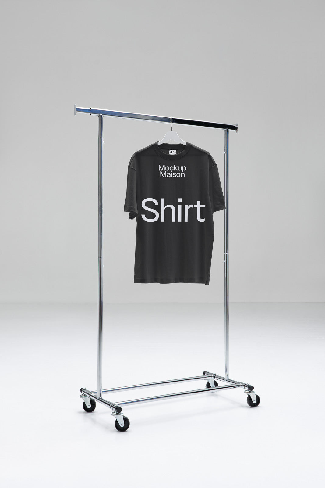 PSD mockup of a black T-shirt with white text hanging on a metal clothing rack in a minimalist studio setting.