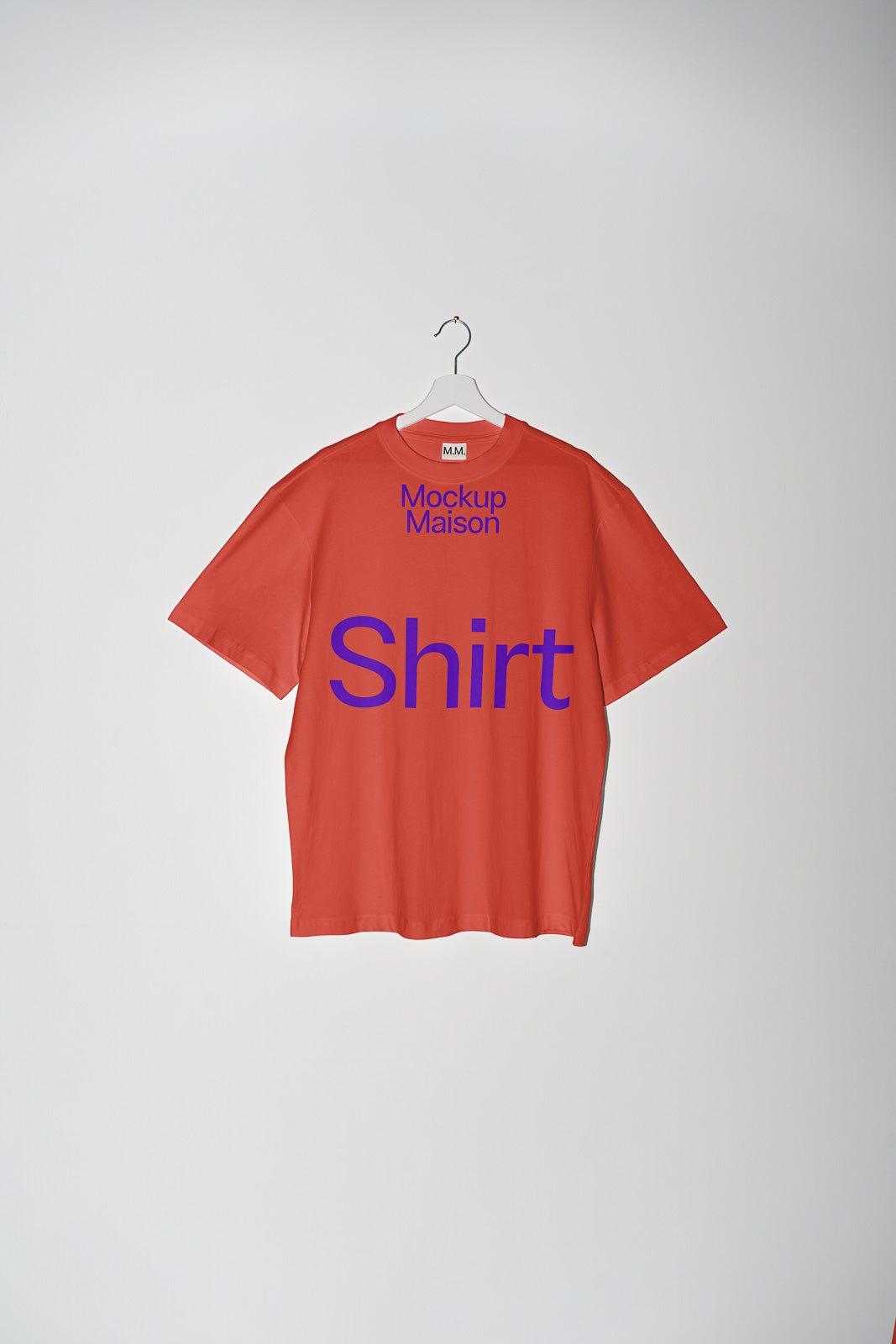 PSD mockup of a red T-shirt hanging on a white hanger, with "Mockup Maison" text at the top and "Shirt" written in bold blue letters on the back.