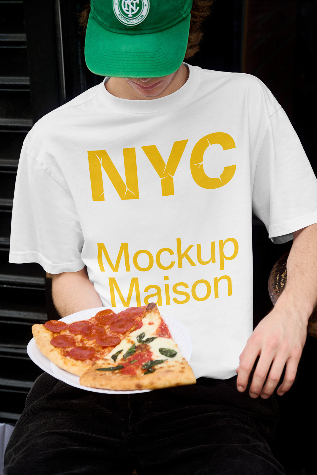PSD mockup of a person holding pizza slices while wearing a white T-shirt with yellow NYC Mockup Maison text.