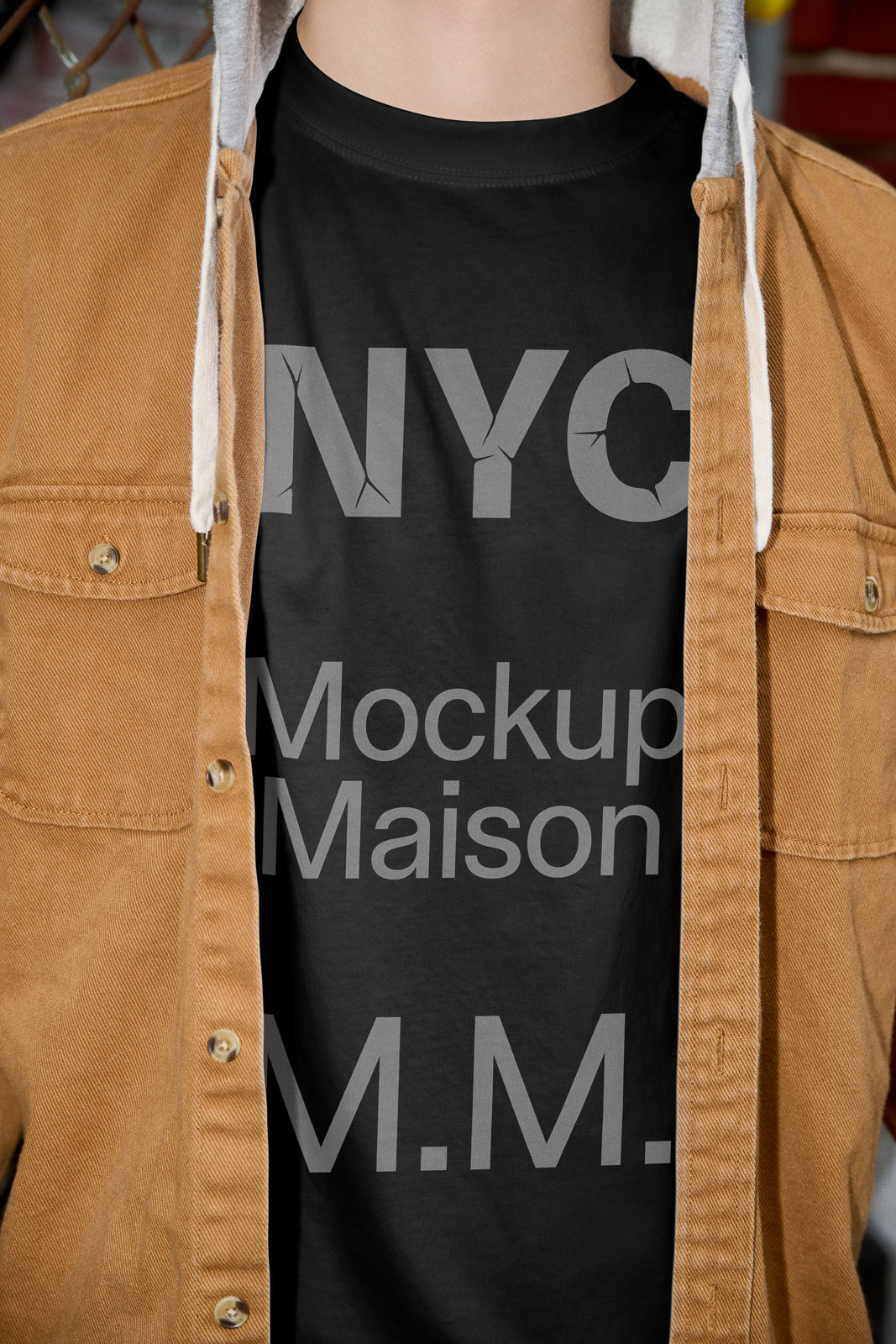 PSD mockup of a black t-shirt under an open brown jacket, displaying large gray text reading "NYC Mockup Maison M.M."