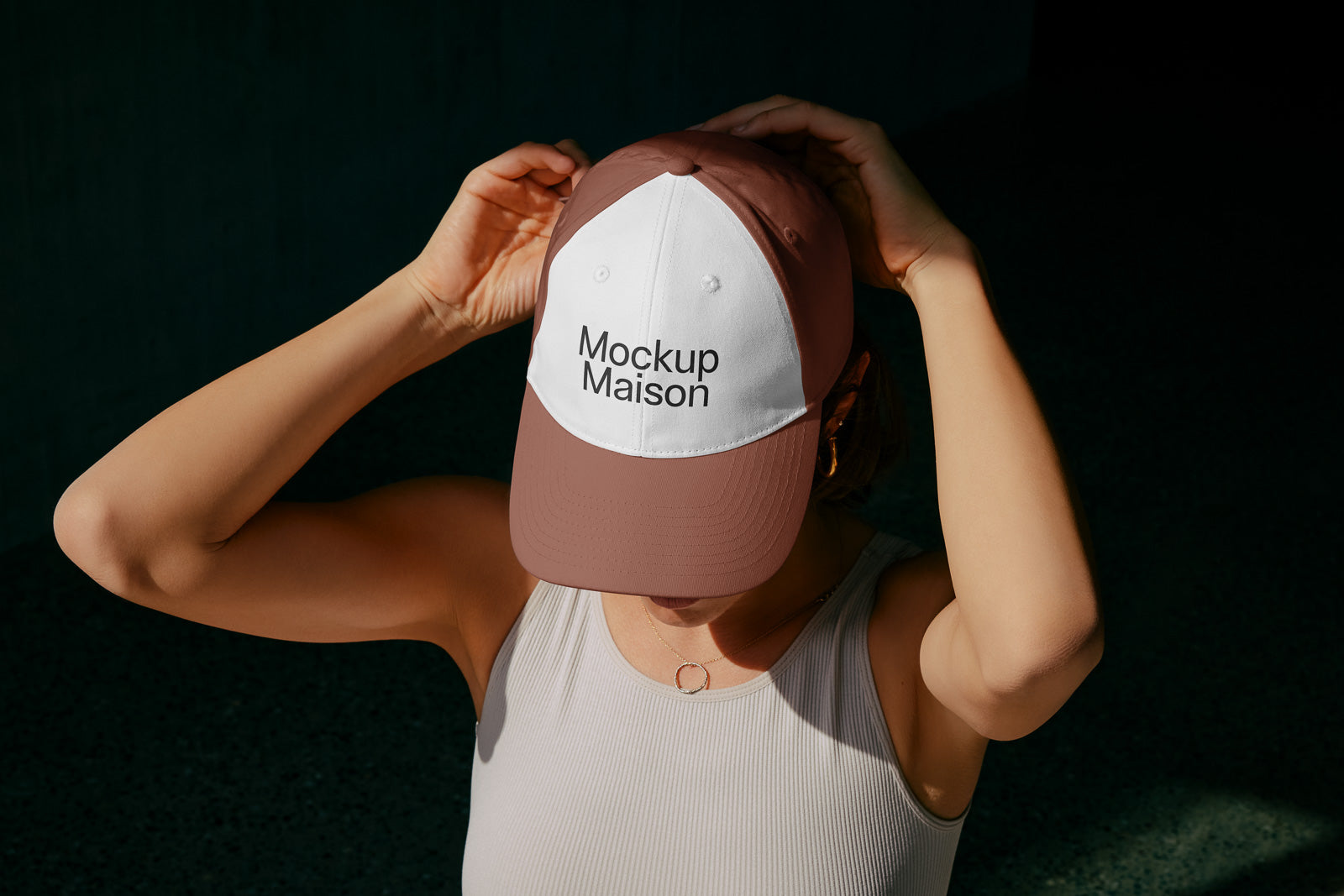 PSD mockup of a two-tone baseball cap featuring the text "Mockup Maison," worn by a person in a sleeveless top adjusting the hat's fit.