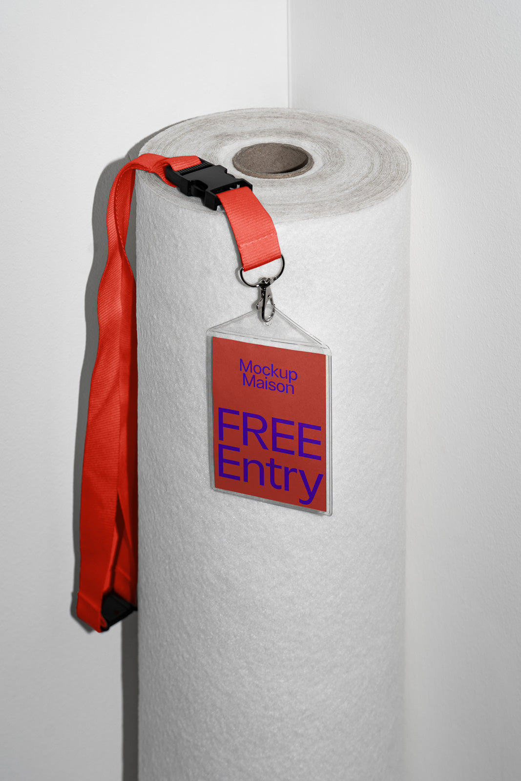 PSD mockup of a large roll of white material with a red lanyard draped over it, attached to a badge reading "Mockup Maison FREE Entry" against a neutral background.