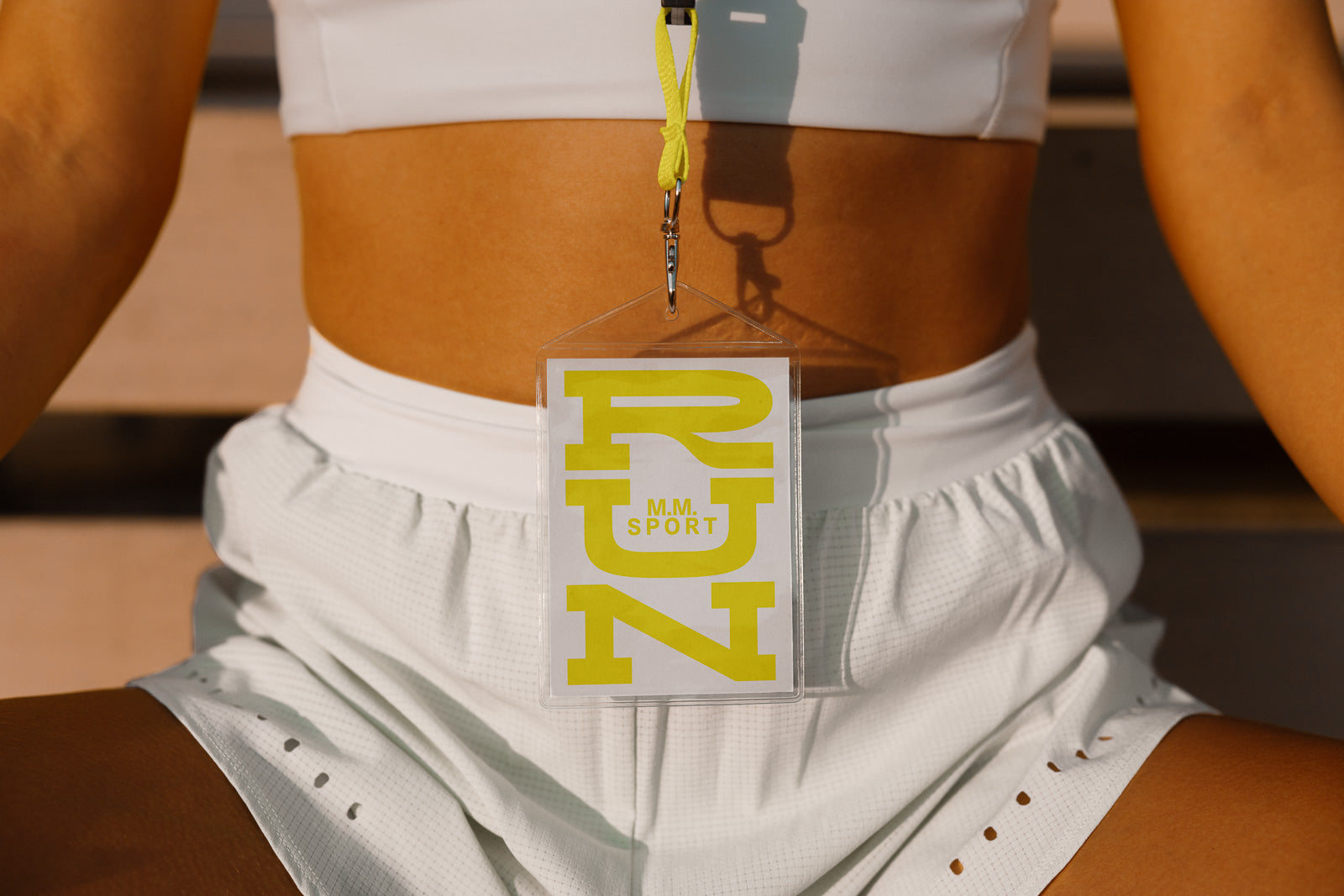 PSD mockup of a lanyard badge labeled "RUN" in yellow, worn by a person in white athletic clothing.