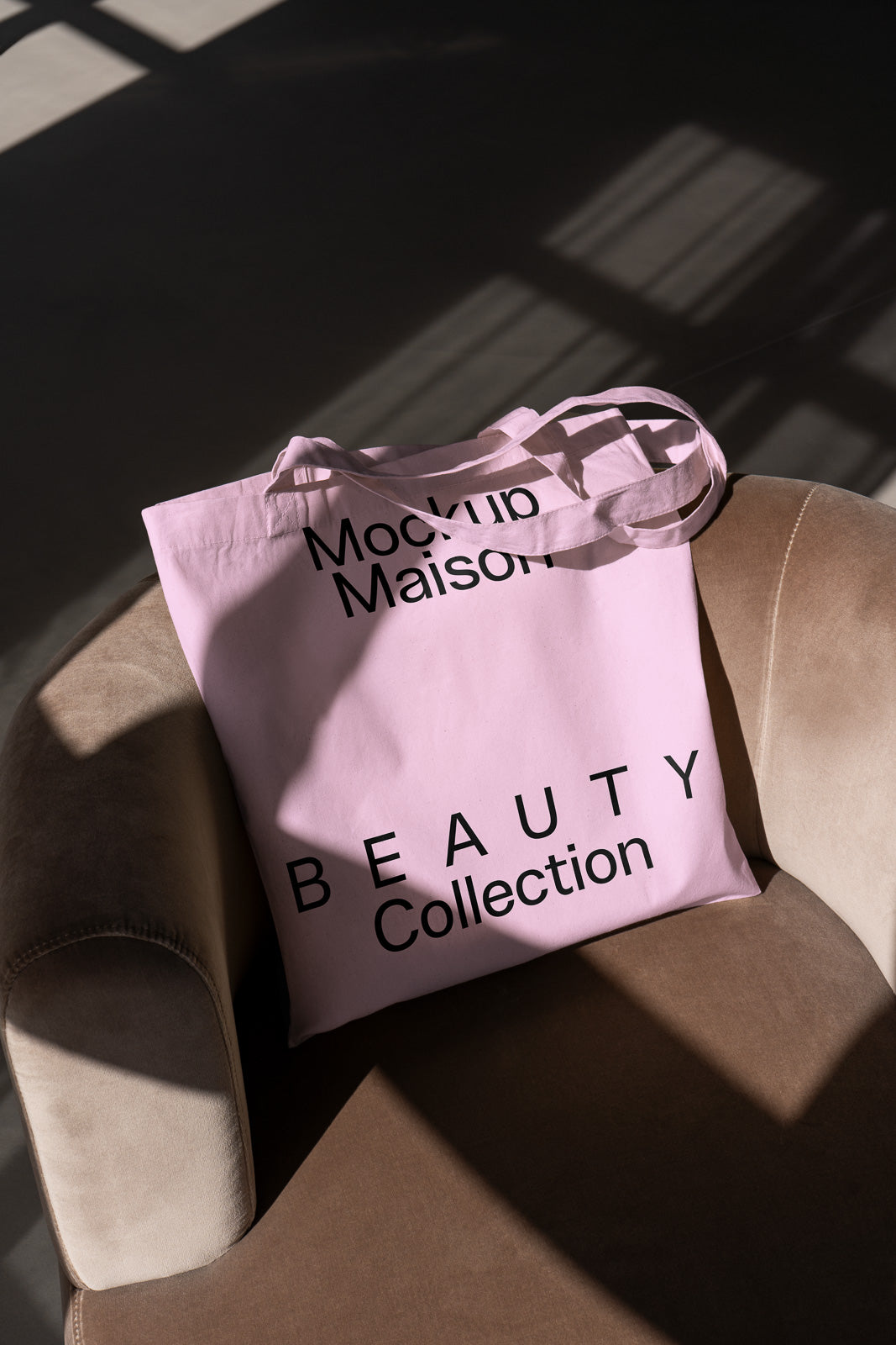 PSD mockup of a pink tote bag with "Mockup Maison" and "Beauty Collection" text, placed on a beige chair with shadow patterns.