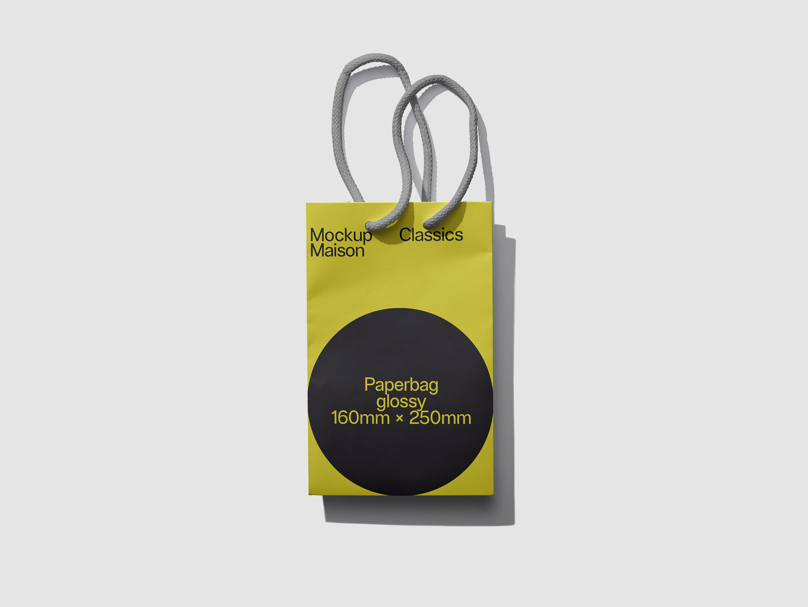 PSD mockup of a small yellow paper bag with gray handles, featuring "Mockup Maison" and "Paperbag glossy 160mm x 250mm" text on the front.