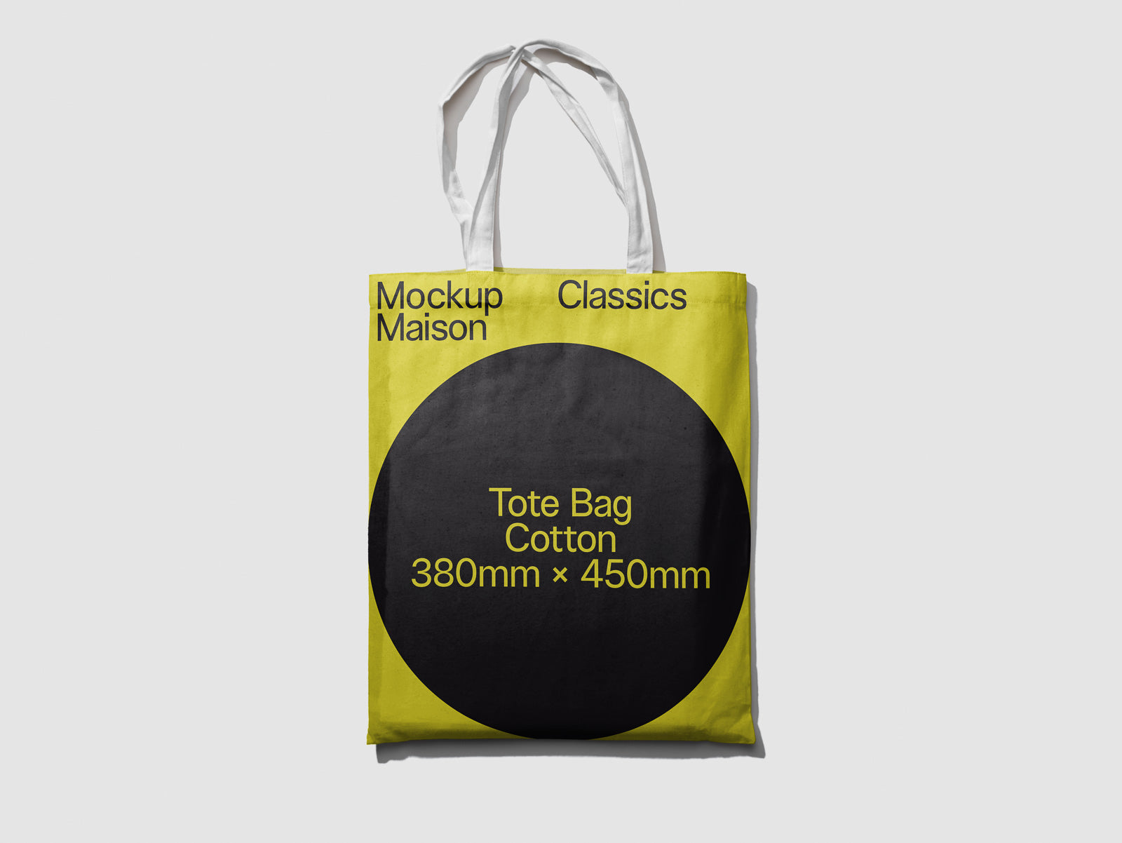 PSD mockup of a cotton tote bag featuring a yellow design with black circle displaying text: "Tote Bag Cotton 380mm x 450mm", labeled "Mockup Maison Classics".