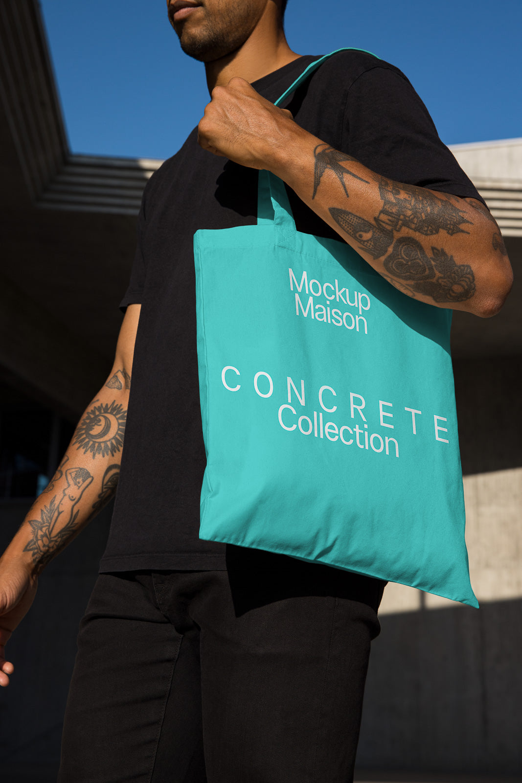 PSD mockup of a person holding a turquoise tote bag with "Mockup Maison CONCRETE Collection" text, against a modern architectural background.