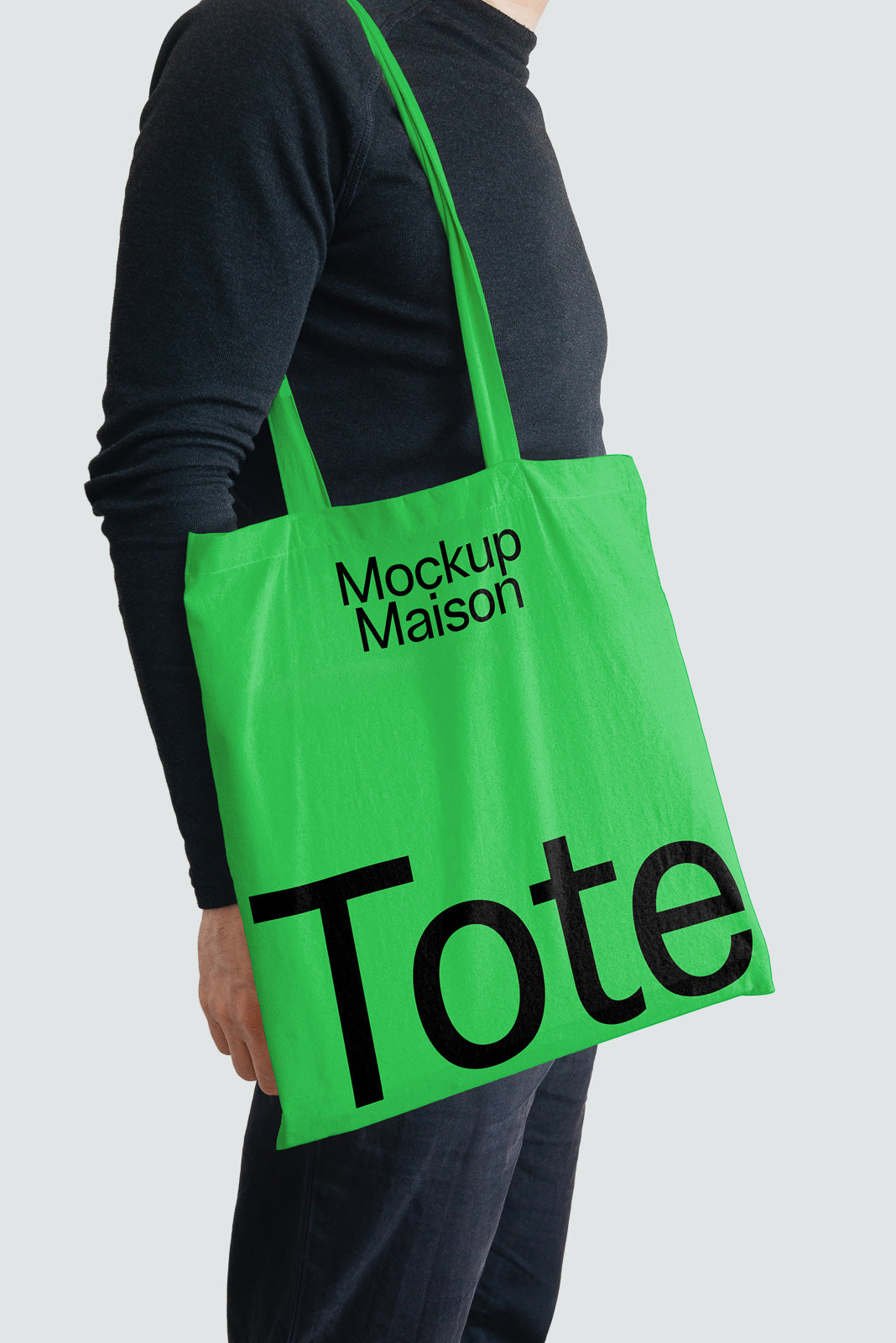 PSD mockup of a person holding a bright green tote bag printed with "Mockup Maison" and "Tote" in bold black letters on a light gray background.
