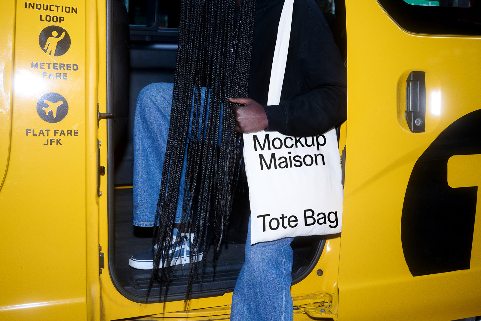 PSD mockup of a person stepping out of a yellow taxi, holding a white tote bag with "Mockup Maison" text, while wearing blue jeans and sneakers.