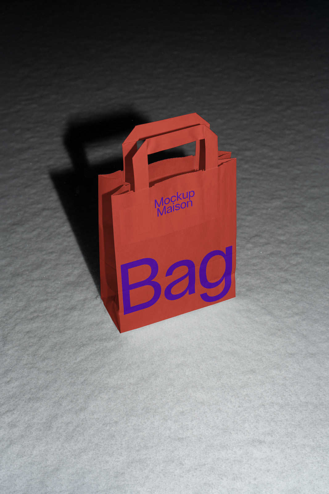 PSD mockup of a red shopping bag standing on a textured gray surface with bold purple text and a shadow.