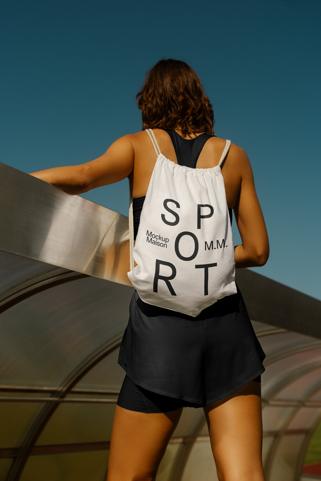 PSD mockup of a person wearing a drawstring backpack with "SPORT" text, standing outdoors against a clear blue sky.