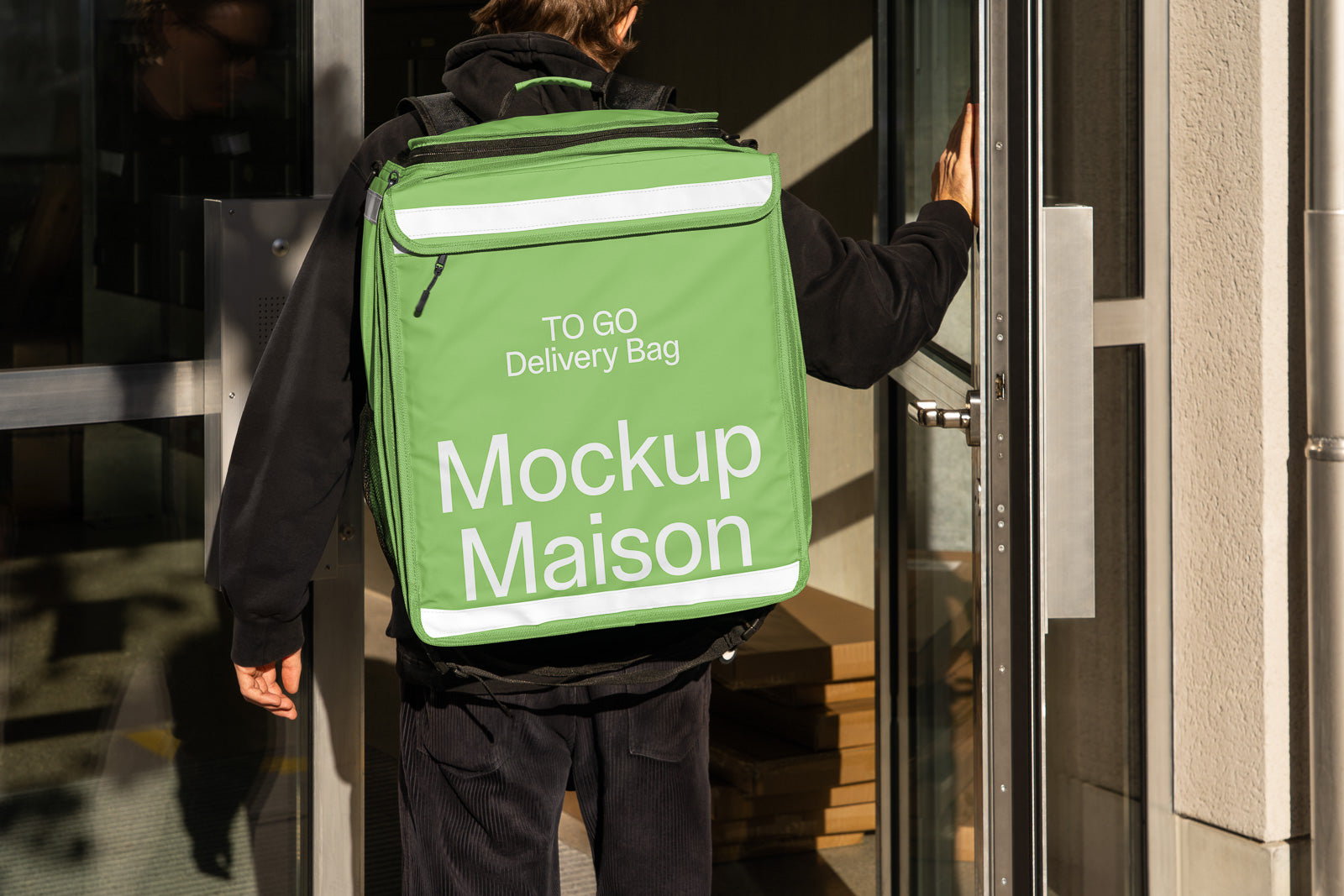 PSD mockup of a person wearing a large green delivery backpack labeled "Mockup Maison" and "TO GO Delivery Bag" opening a glass door.