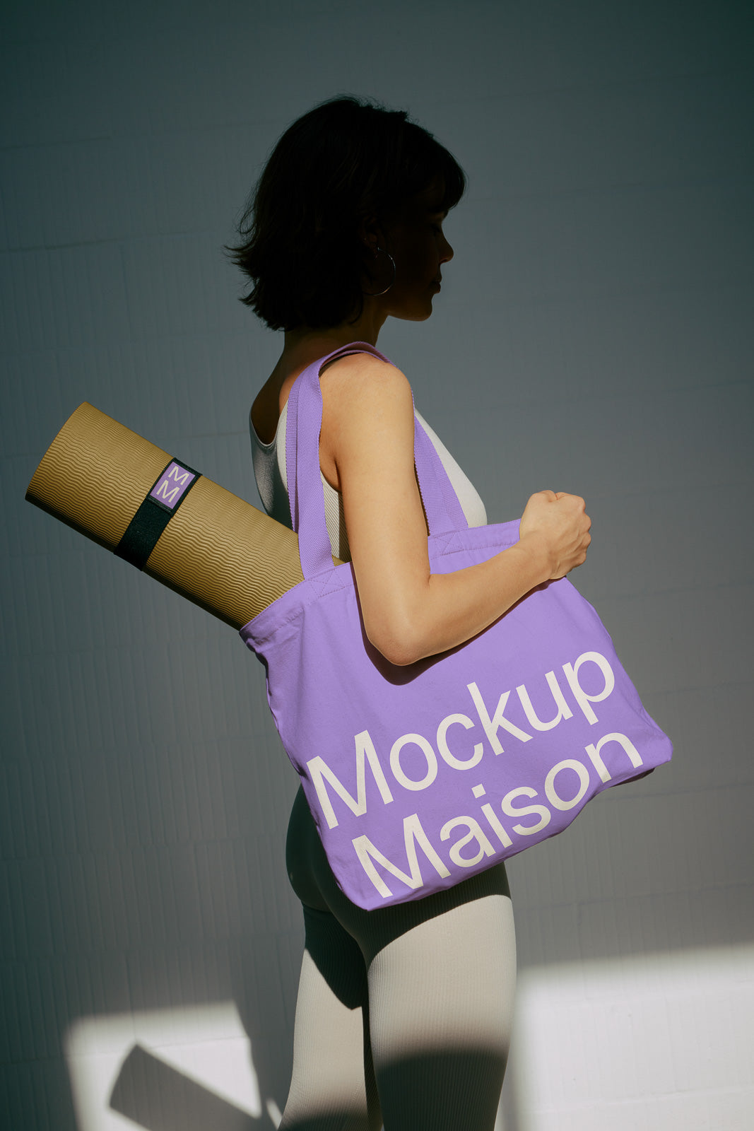 PSD mockup of a person carrying a purple tote bag with "Mockup Maison" text, holding a yoga mat in a strap over their shoulder.