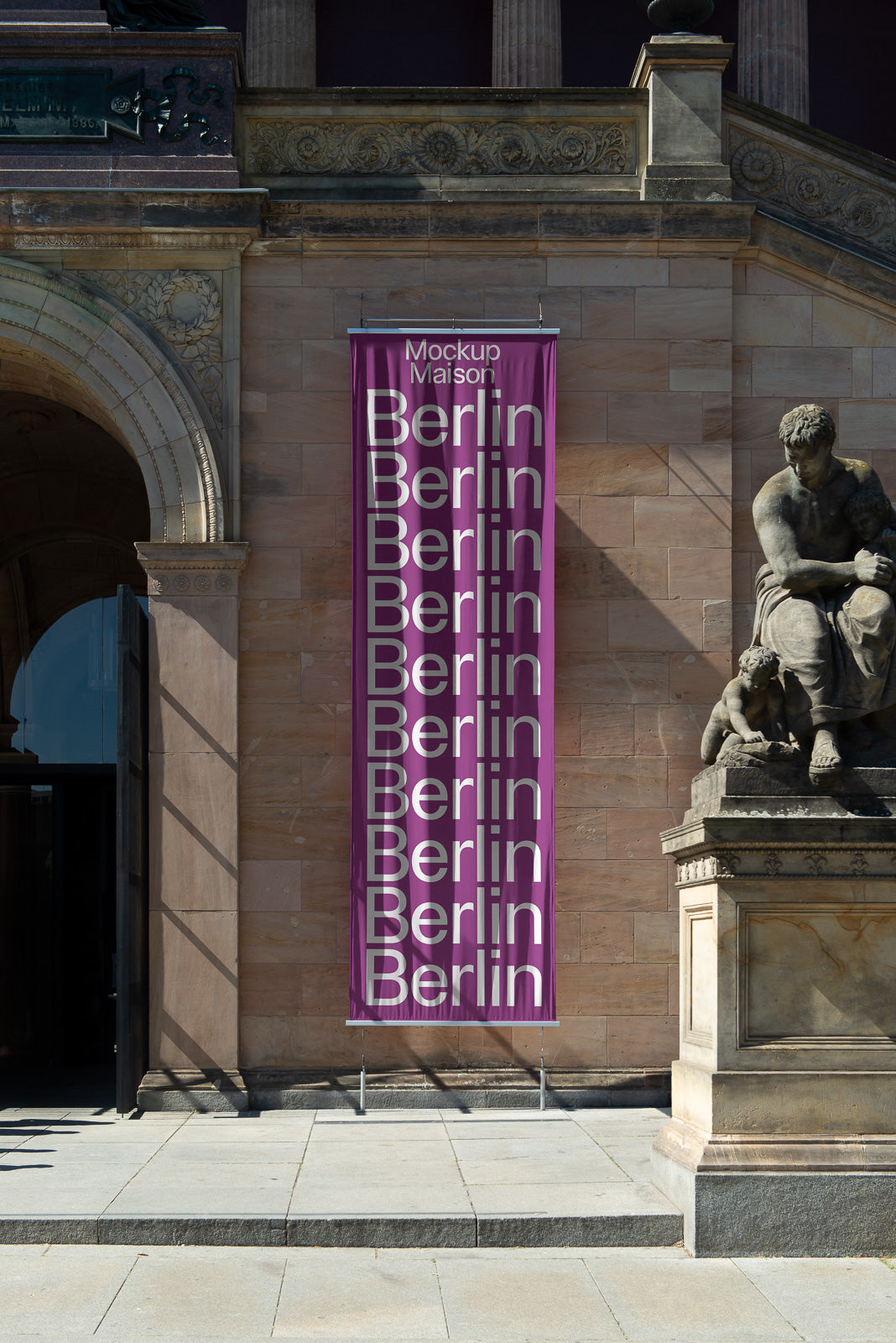 PSD mockup of a vertical banner with "Berlin" printed repeatedly in white on a purple background, displayed against a historic stone facade with a sculpture nearby.