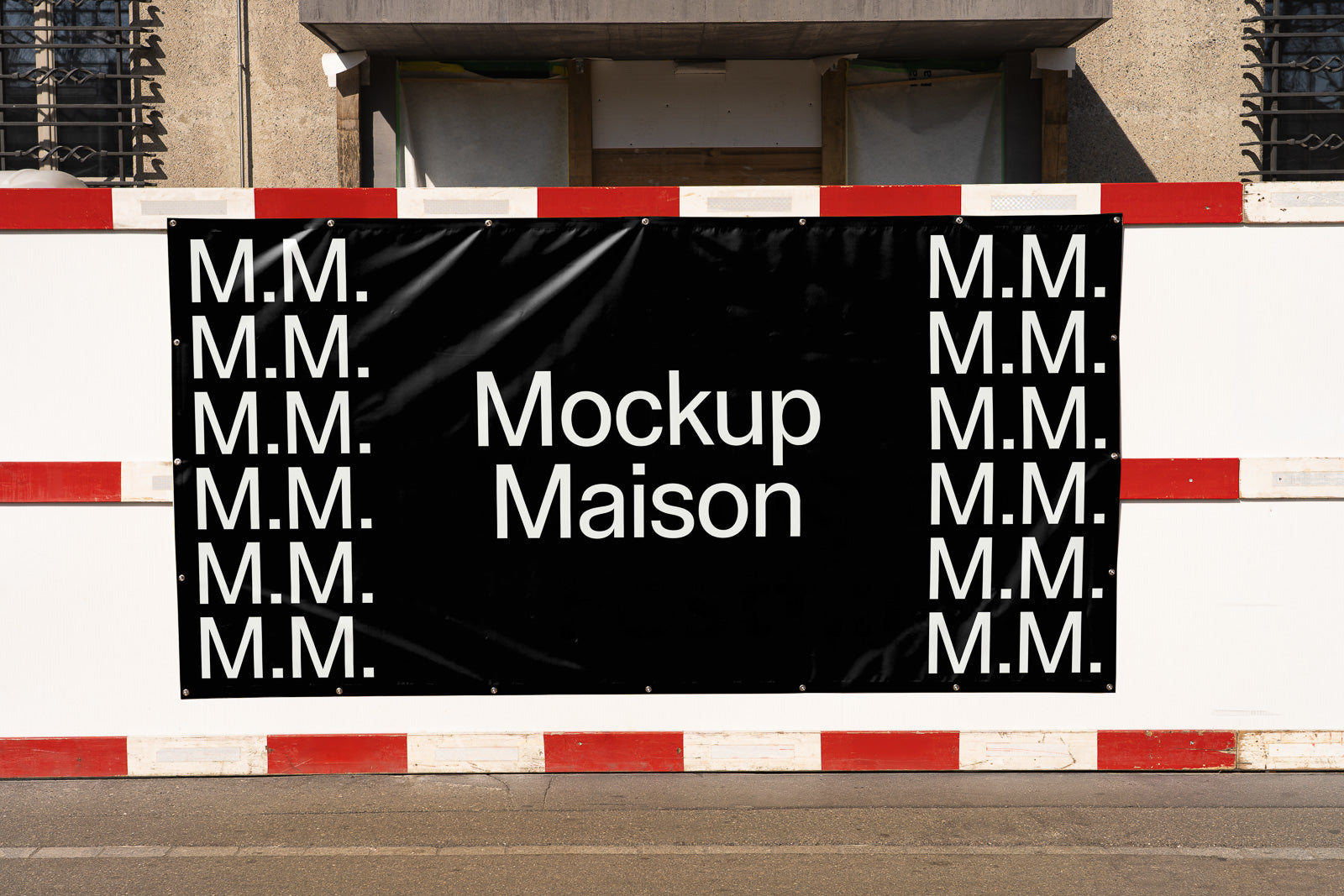 PSD mockup of a black banner displayed on a construction fence with "Mockup Maison" text and repeated "M.M." initials on the sides.