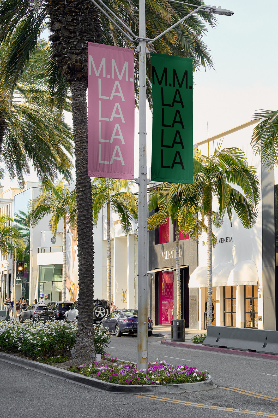PSD mockup of street banners featuring pink and green designs with text, set against a backdrop of palm trees and luxury storefronts on a sunny day.