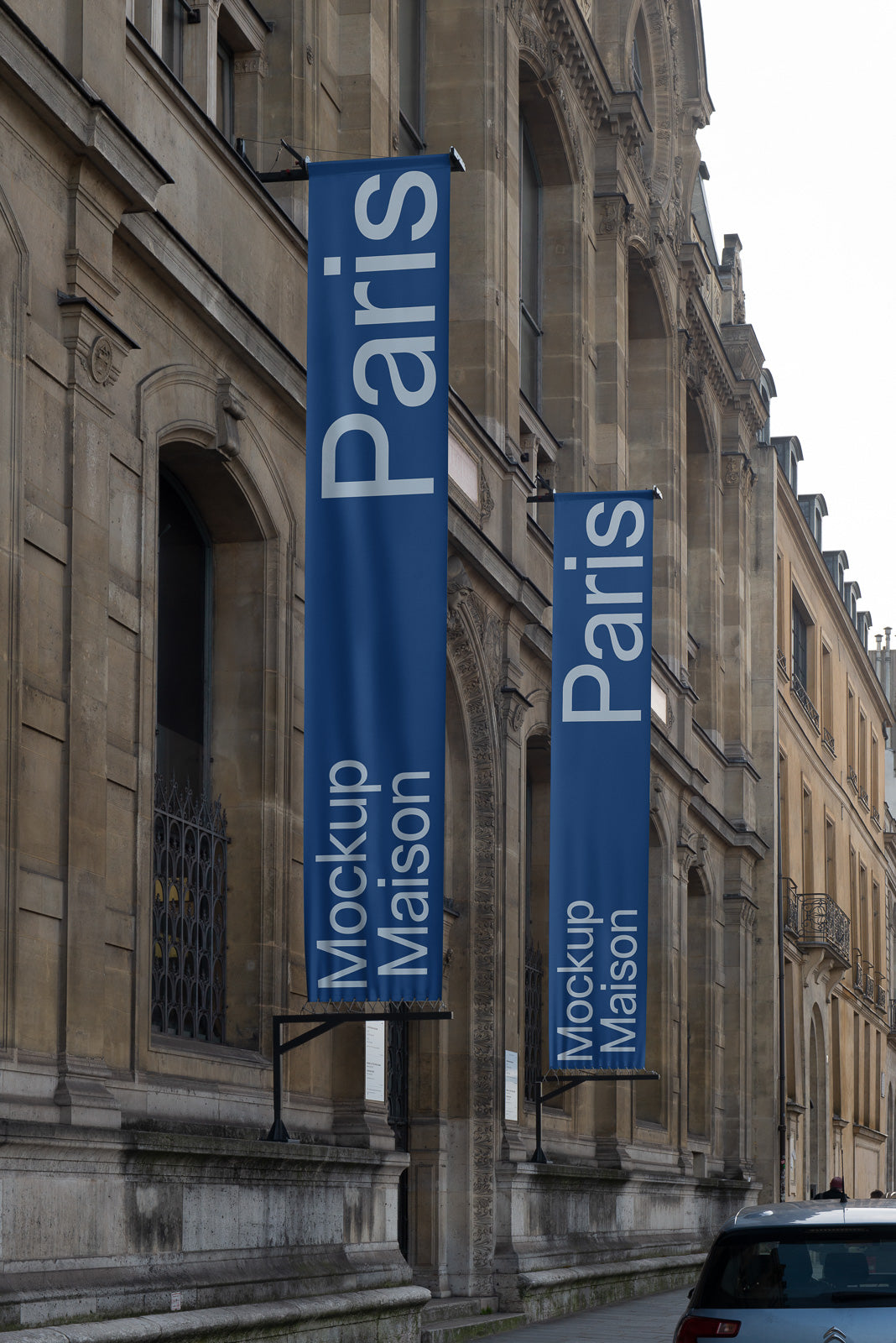 PSD mockup of vertical blue banners with the text "Paris MockUp Maison" hanging on an ornate stone building, viewed from a street perspective.