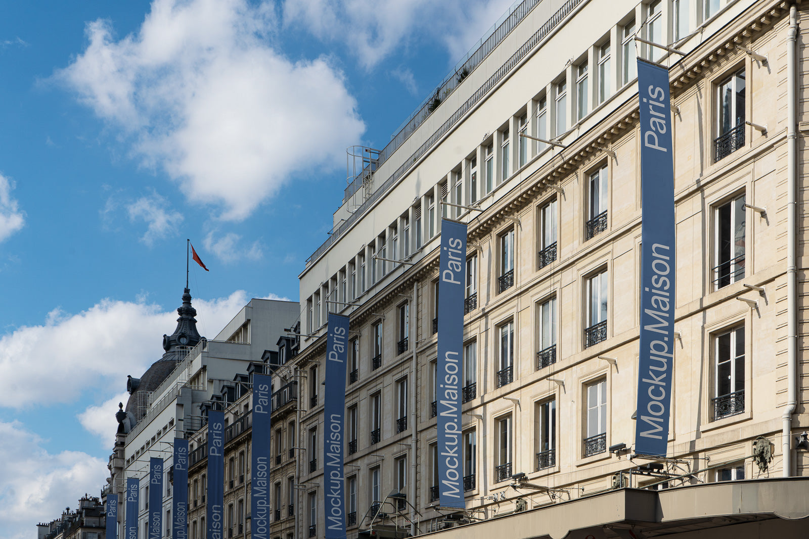 PSD mockup of Parisian building facade with blue vertical banners displaying "Mockup Maison" under a clear blue sky with scattered clouds.