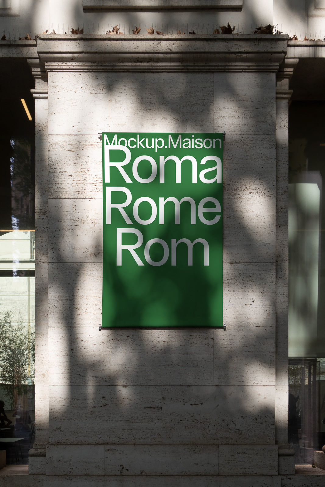 PSD mockup of a green banner on a stone wall displaying the text "Mockup.Maison Roma Rome Rom" with shadows cast across the surface.