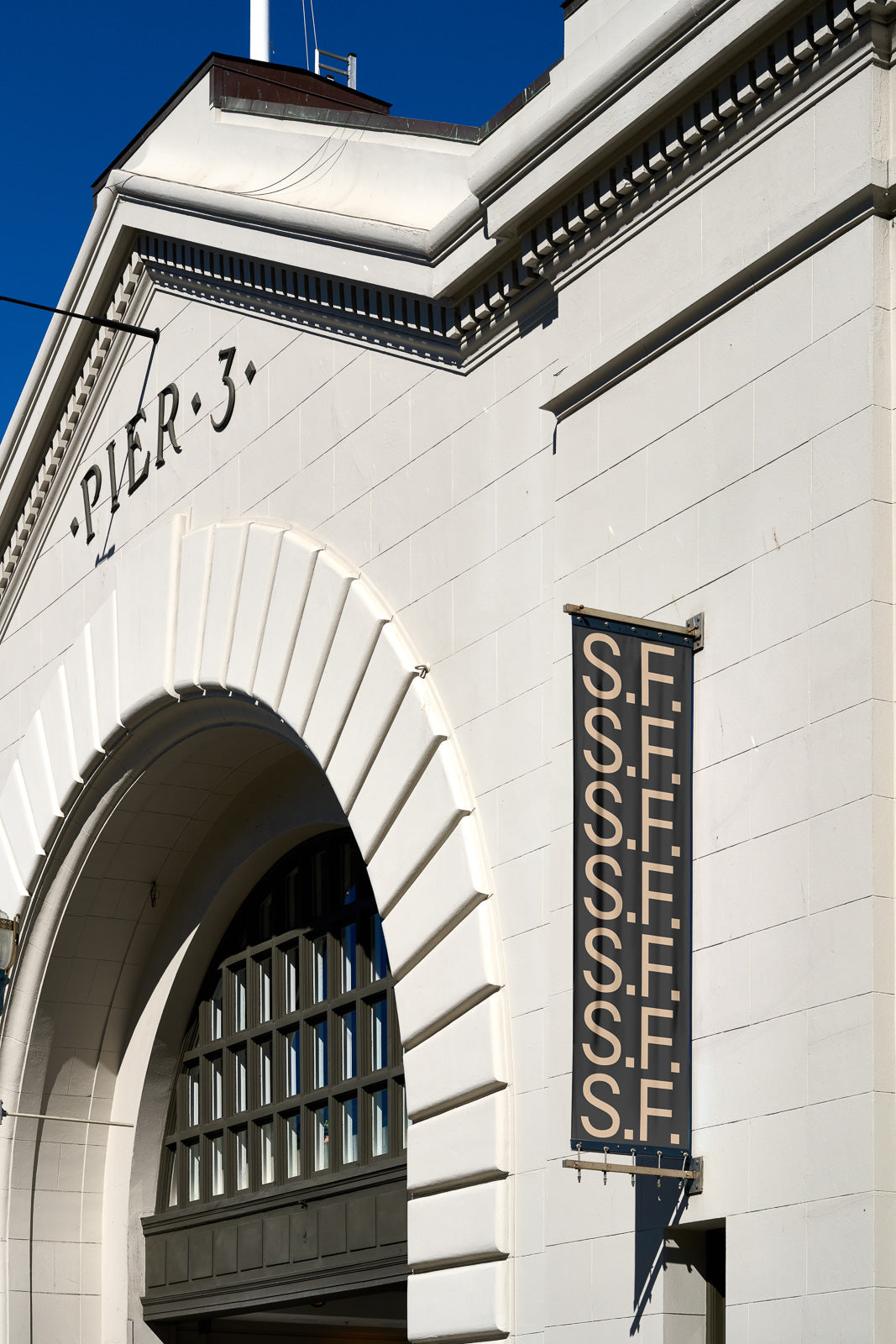 PSD mockup of an arched entrance labeled "Pier 3" with a banner reading "S.S.F.F," highlighting architectural details against a clear sky.