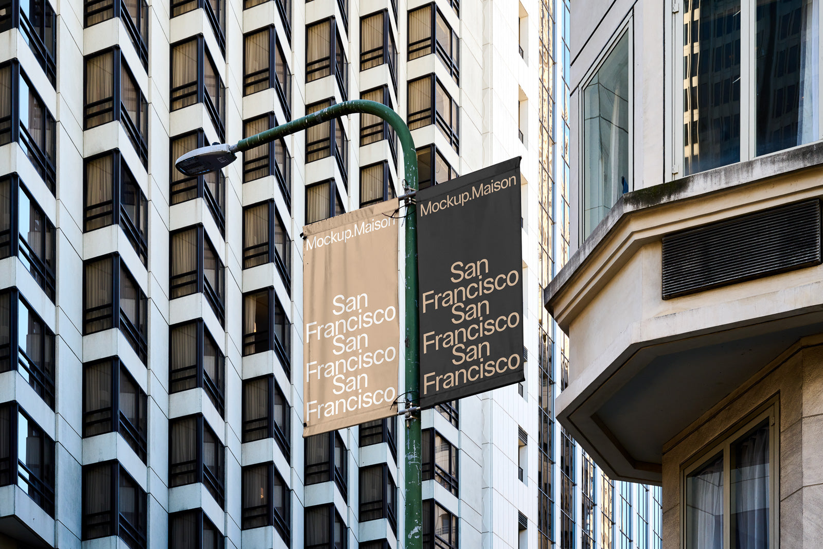 PSD mockup of two vertical banners on a streetlight against a background of modern high-rise buildings, displaying the text "San Francisco" and "Mockup.Maison".