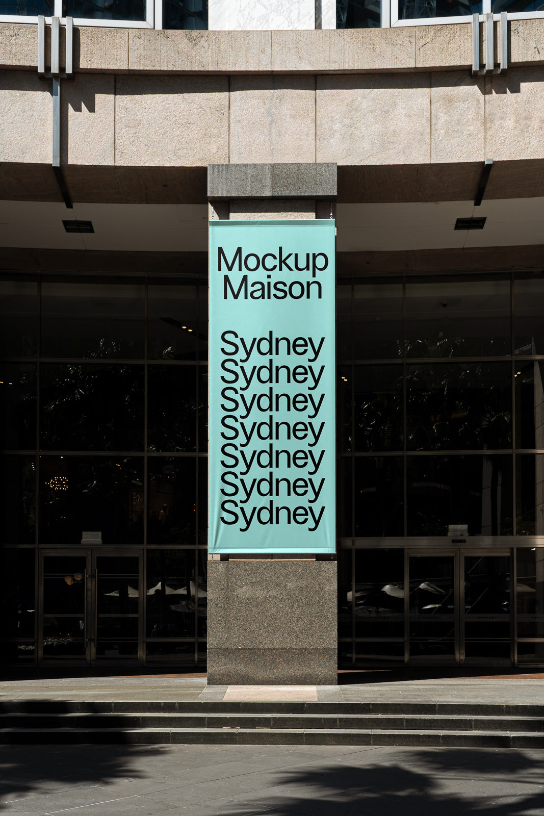 PSD mockup of a vertical banner displayed on a building's stone column, featuring the text "Mockup Maison Sydney" repeated in bold black font on a light teal background.