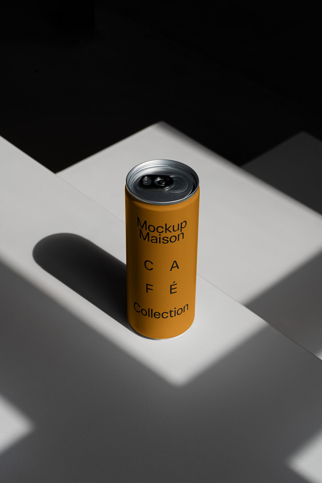PSD mockup of a yellow can labeled "Mockup Maison Café Collection" sitting on a white surface with dramatic lighting and shadow.