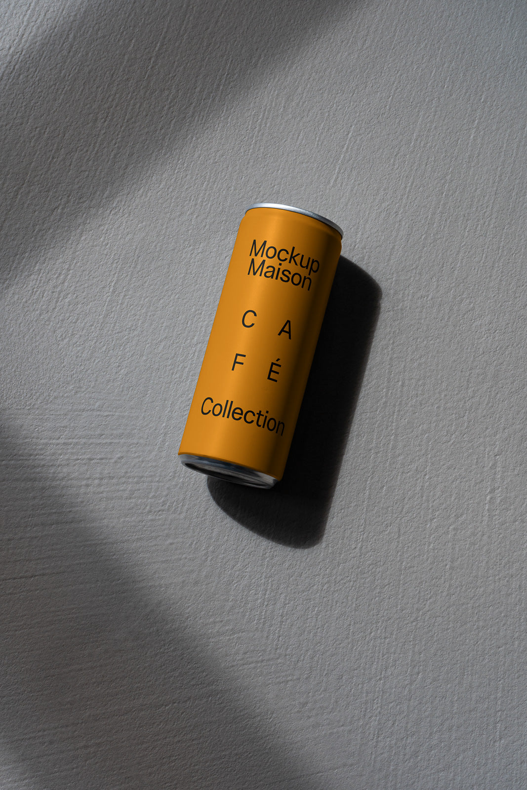 PSD mockup of a yellow can labeled "Mockup Maison Café Collection" casting a shadow on a textured gray surface.