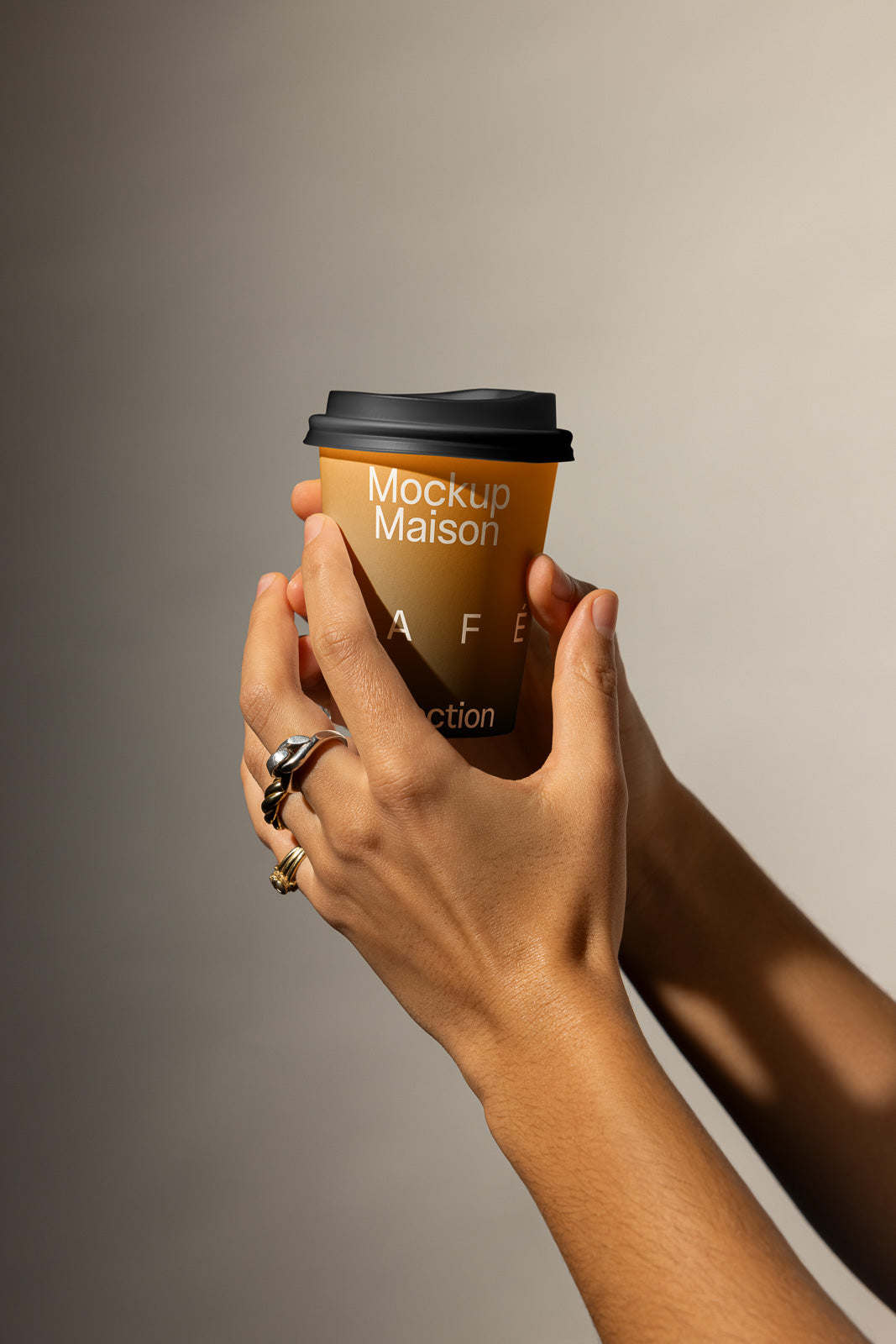 PSD mockup of hands holding a brown coffee cup with Mockup Maison text, featuring a black lid and neutral background.