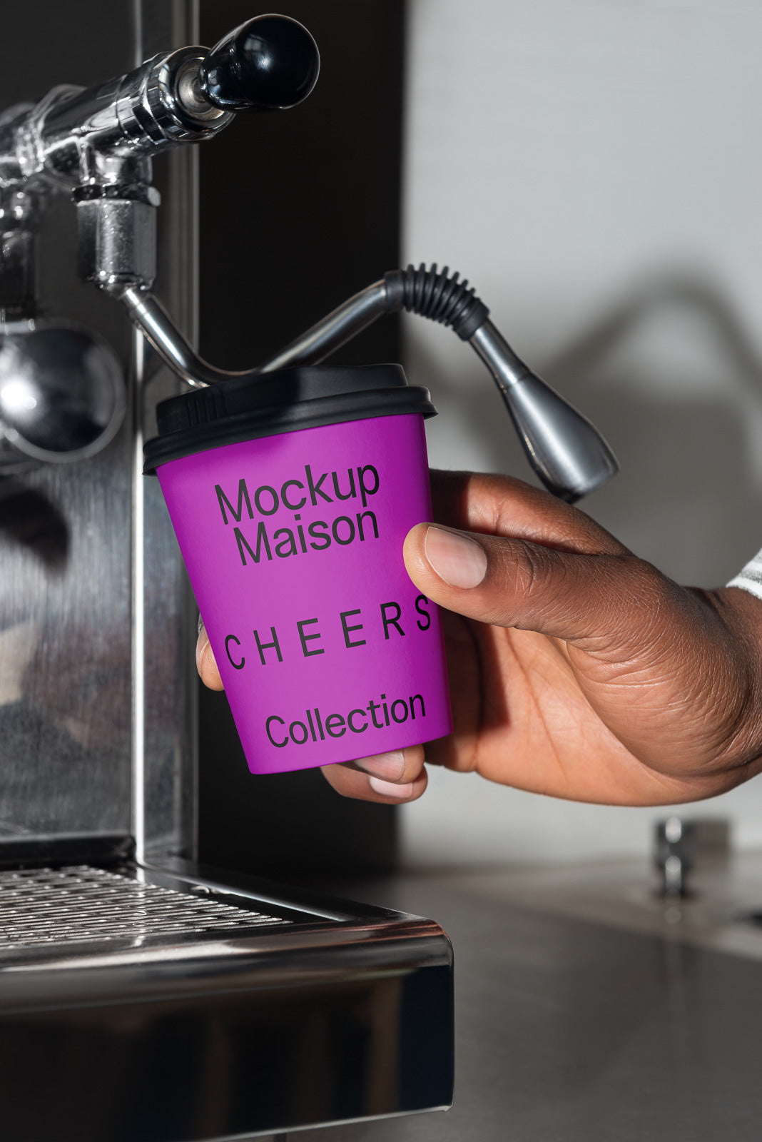 PSD mockup of a hand holding a purple cup labeled "Mockup Maison Cheers Collection" near a coffee machine nozzle.
