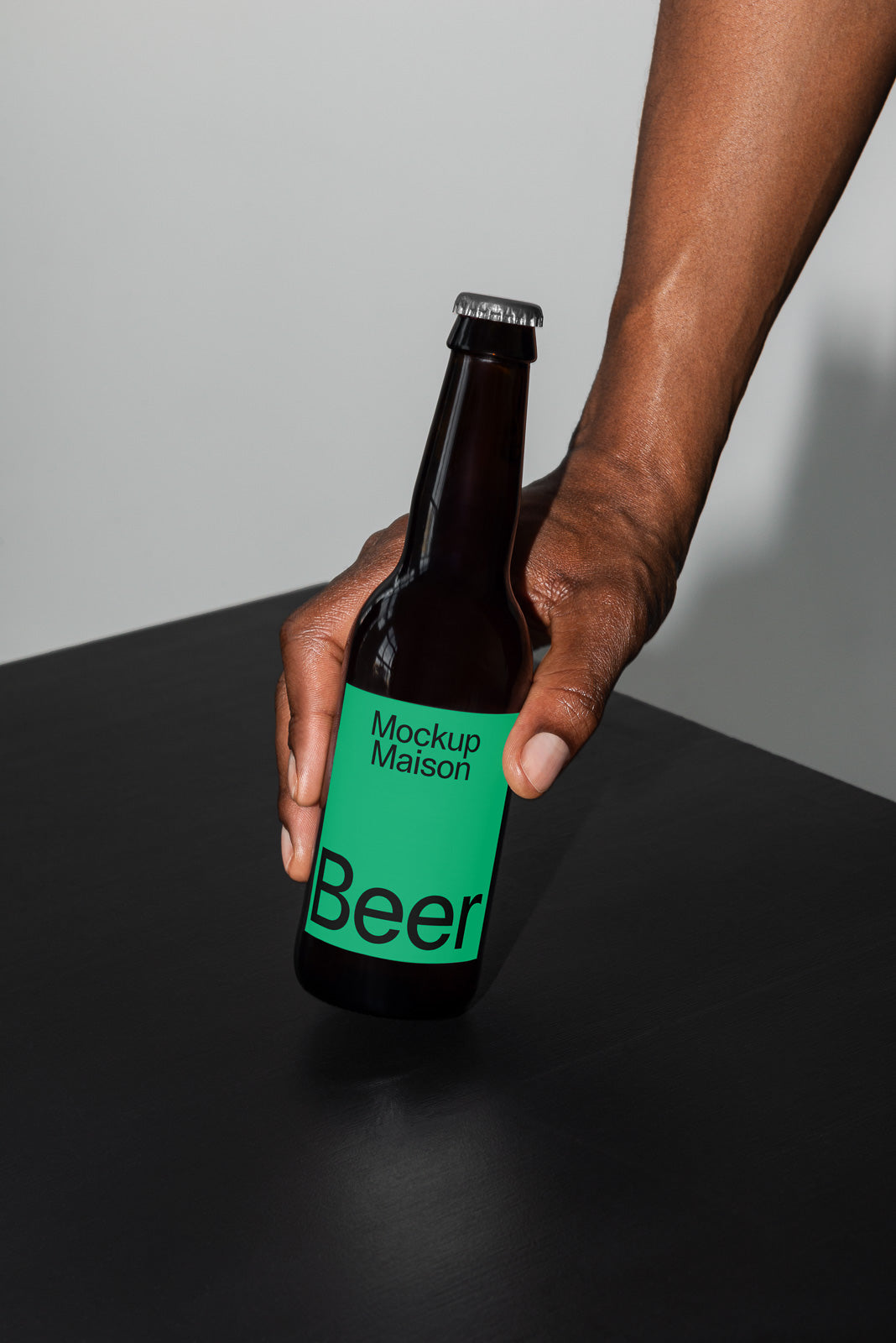 PSD mockup of a green-labeled beer bottle being held over a dark surface, displaying the text "Mockup Maison Beer" prominently.