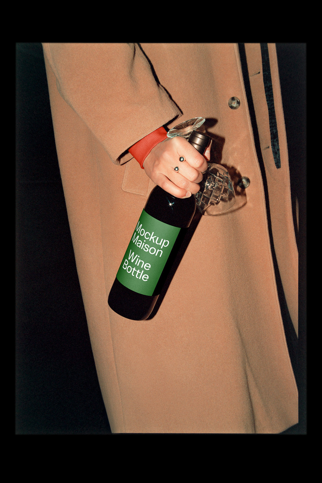 PSD mockup of a hand holding a wine bottle with a green label, partially wrapped in a beige coat, creating a stylish presentation backdrop.