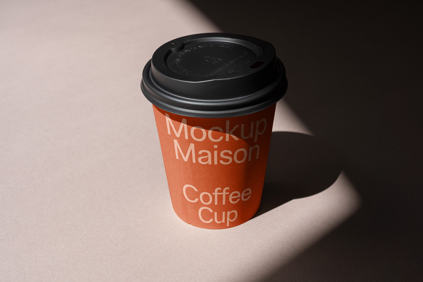 PSD mockup of a coffee cup with black lid, featuring the text "Mockup Maison Coffee Cup" on an orange background, placed on a neutral surface.