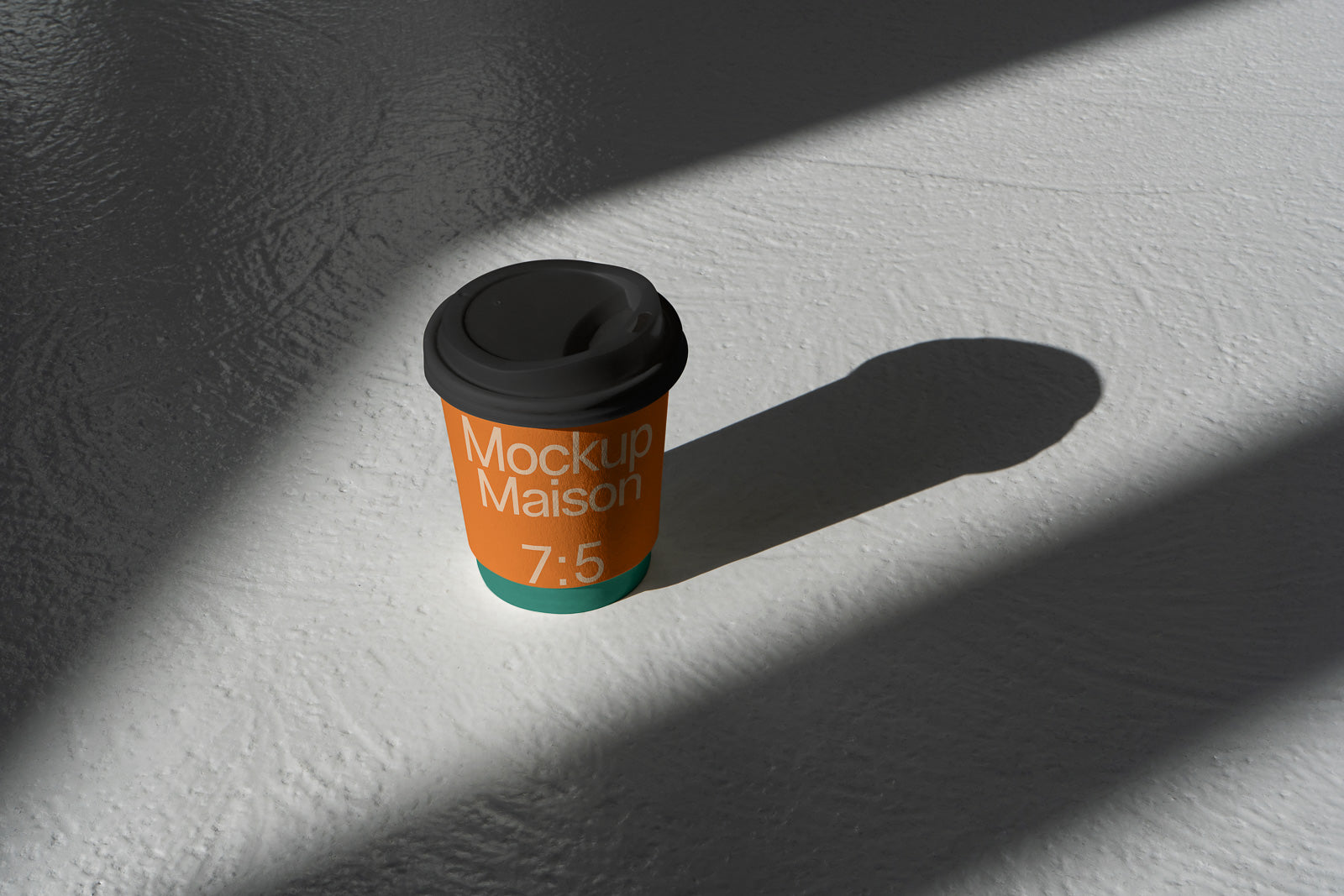 PSD mockup of a takeaway coffee cup labeled "Mockup Maison 7:5" with a shadow on a textured surface.