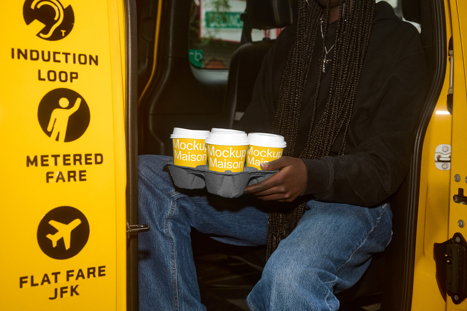 PSD mockup of coffee cups held by a person sitting in a vehicle, with bold text “Mockup Maison” on each cup, next to a yellow taxi door.